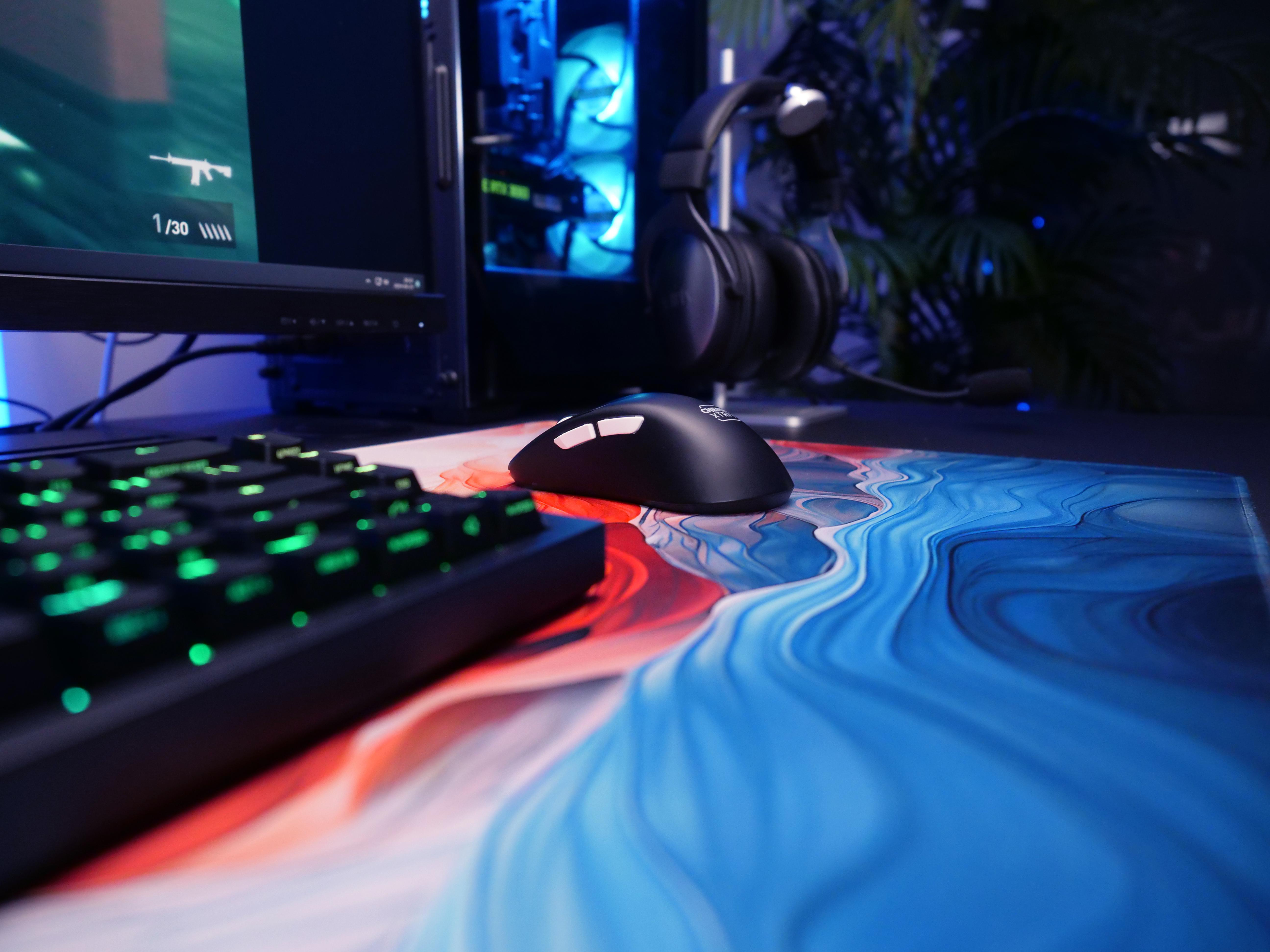 Ein Gaming-Setup mit einer schwarzen Maus, Tastatur und farbenfrohem Mousepad.