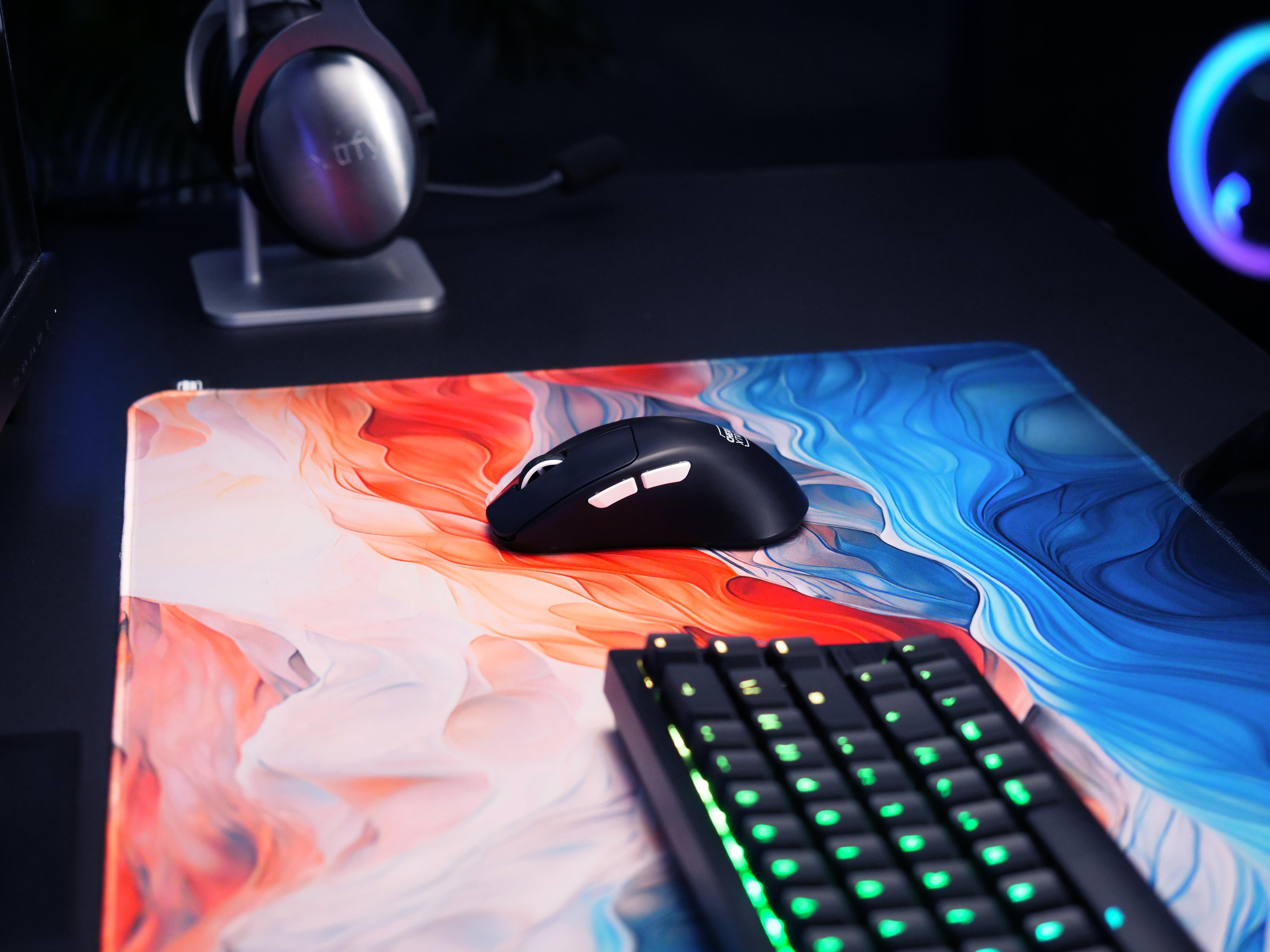 Nahaufnahme eines Gaming-Setups mit Tastatur, Maus und farbenfrohem Mauspad.