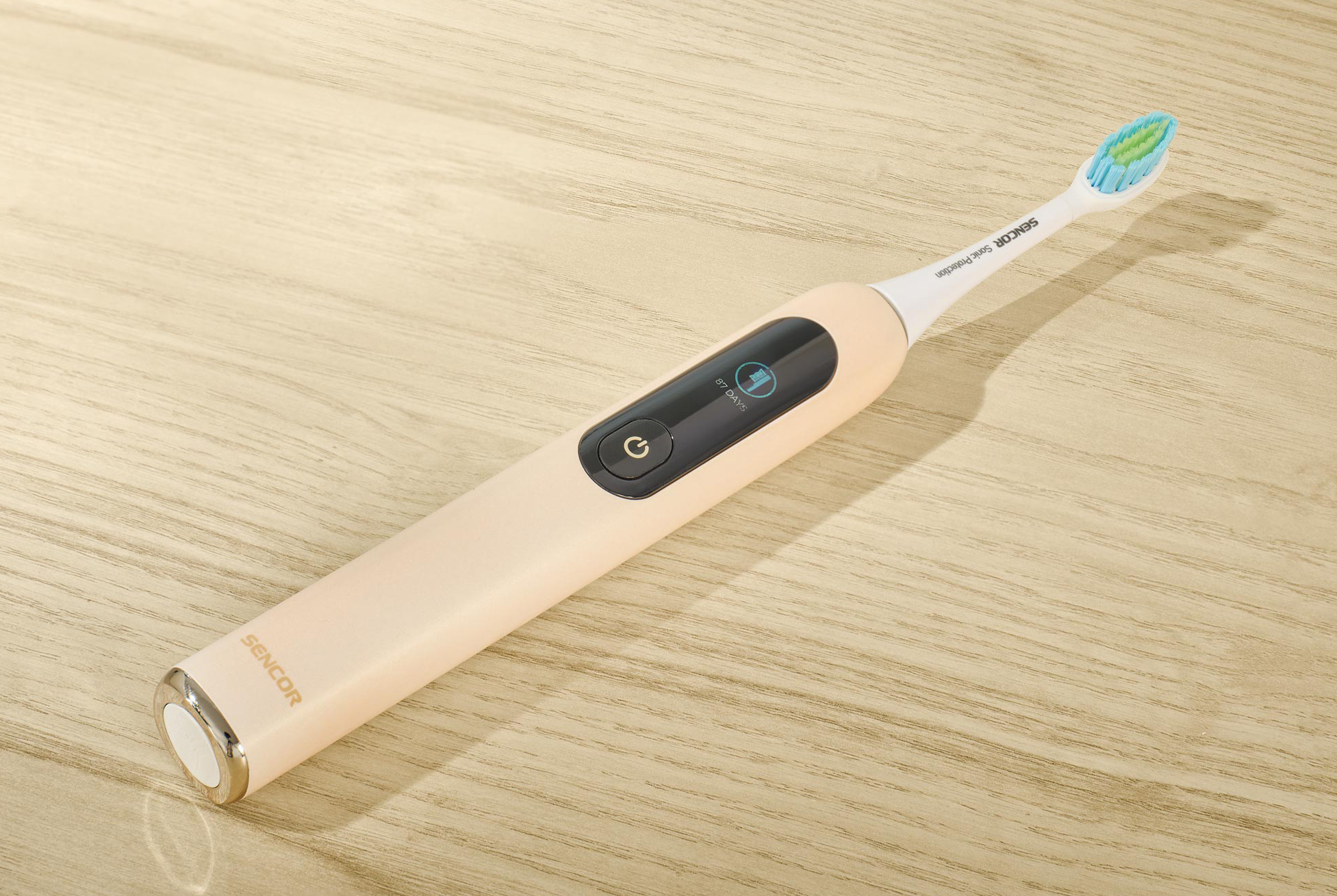 Egy bézs elektromos fogkefe egy fa felületen.