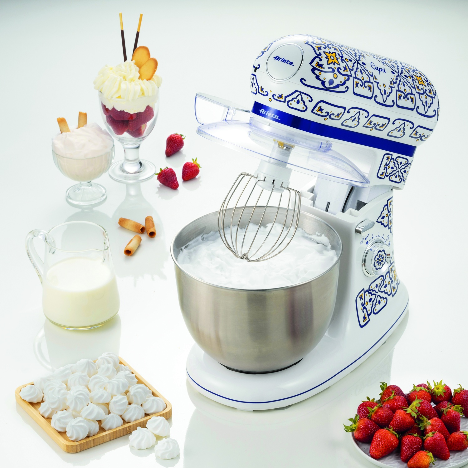 Impastatrice Ariete Capri con ingredienti su sfondo bianco. Ciotola con panna montata, frutta.