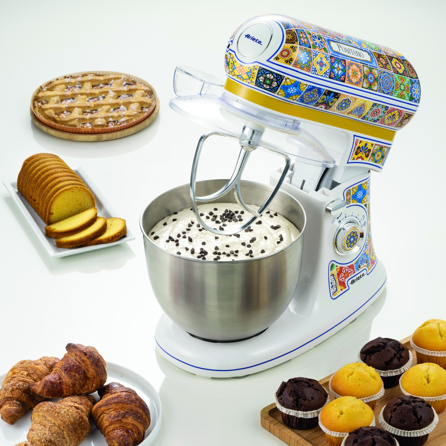 Un mixer da cucina con pasticcini e prodotti da forno su superficie bianca.