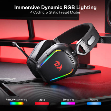 Fekete gamer headset RGB világítással, mikrofonnal és vezérlőkkel. A headset egy asztalon van, billentyűzettel.