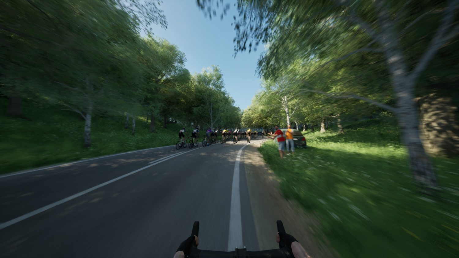 Ciclistas montando en una carretera, vistos desde una perspectiva en primera persona, con árboles al fondo.