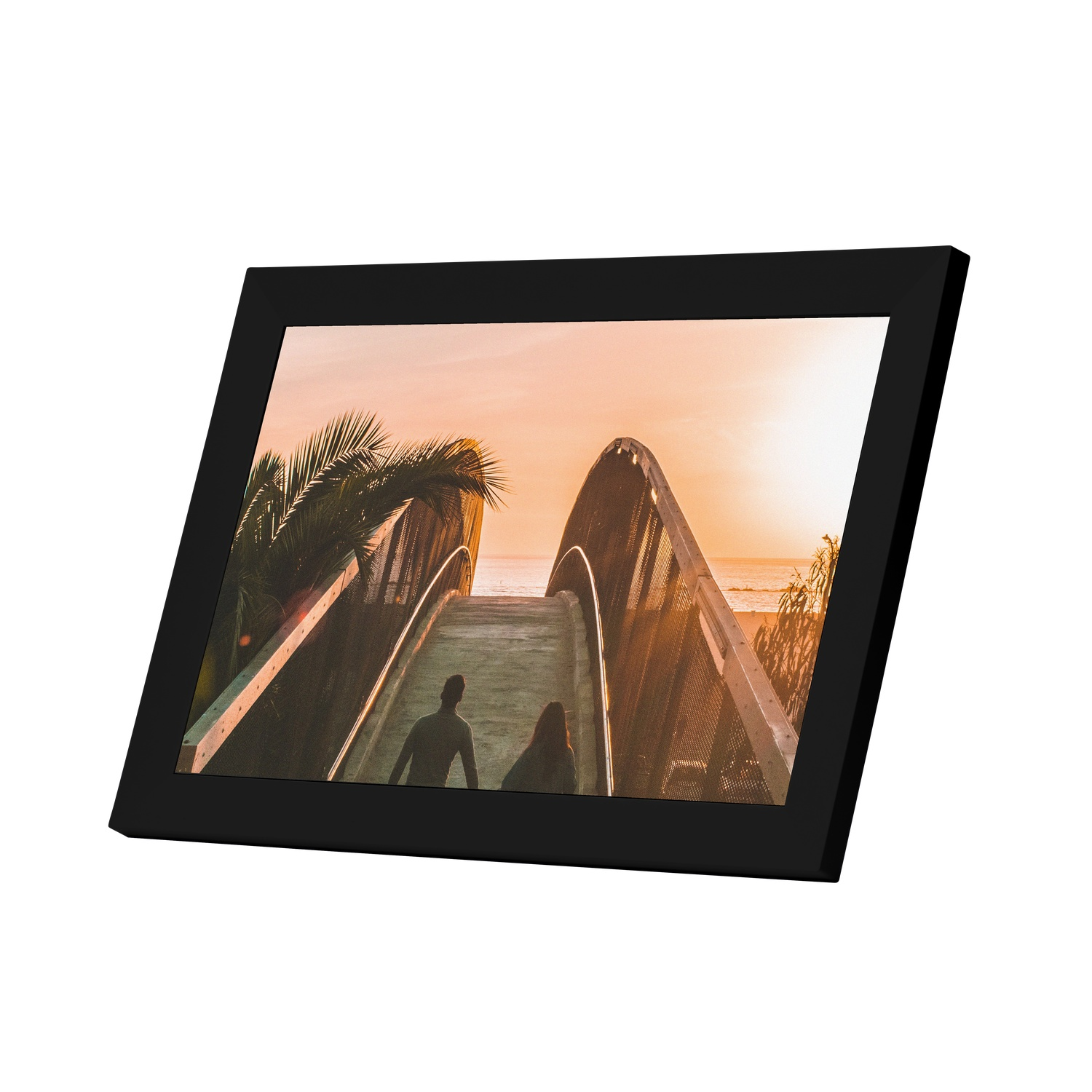 Black framed picture with a bridge scene during sunset, with two silhouettes.