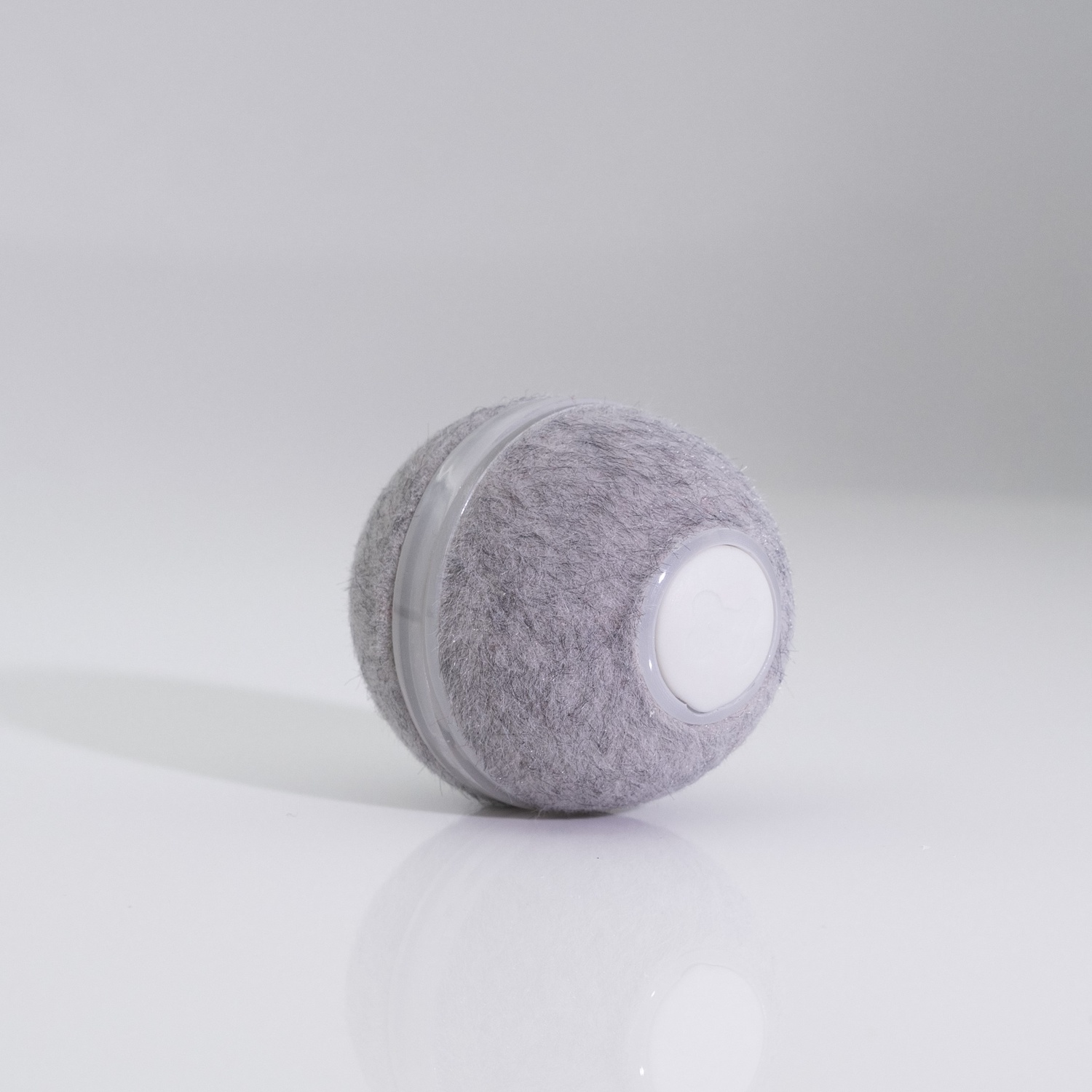 Gray plush ball with a white plastic band and a white button on it.