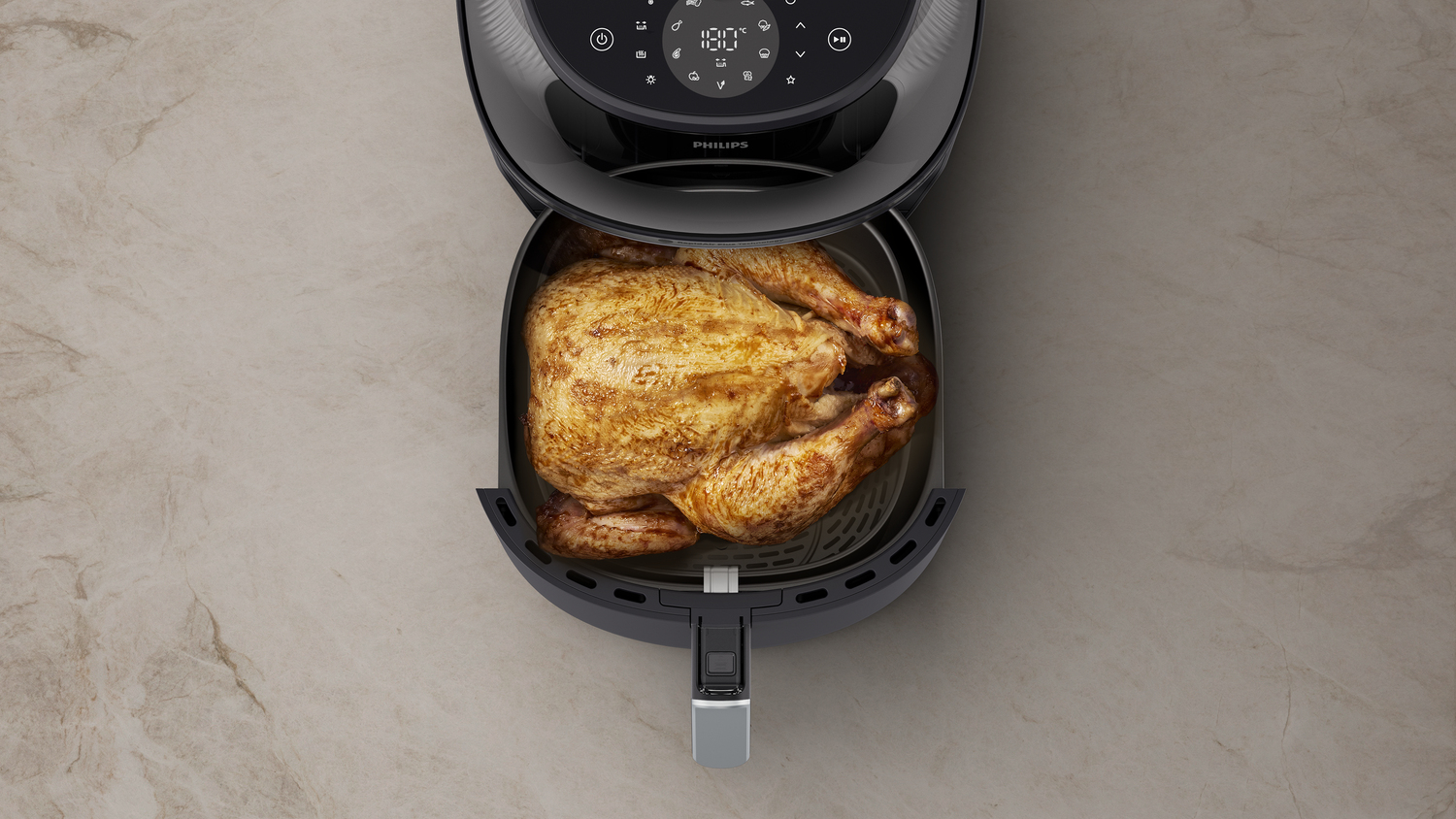 Freidora de aire con pollo asado dentro y exterior negro y plateado.