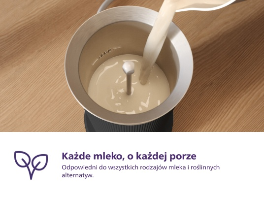 Spieniacz do mleka z mlekiem w środku, zbliżenie, na drewnianej powierzchni.