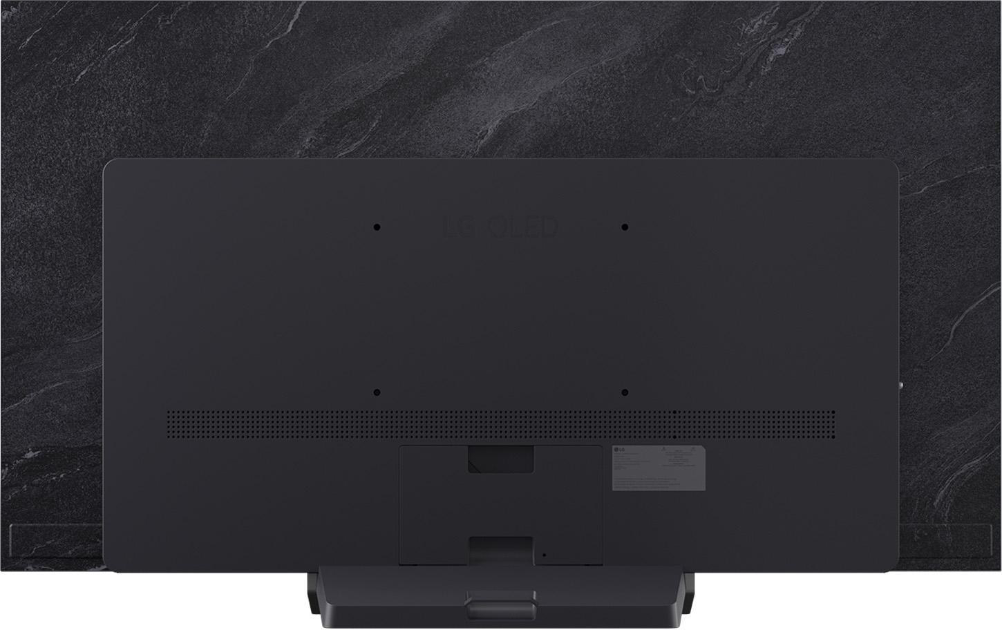 Rückseite eines großen schwarzen Fernsehers an einer strukturierten grauen Wand. Kleiner Ständer unten.