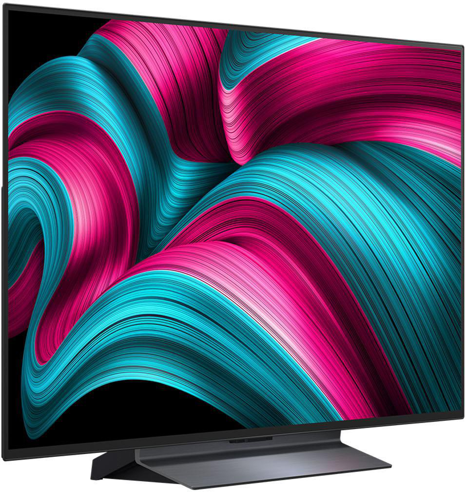 Seitenansicht eines modernen Fernsehers. Der Bildschirm zeigt ein lebendiges, abstraktes Design in Rosa und Blau.
