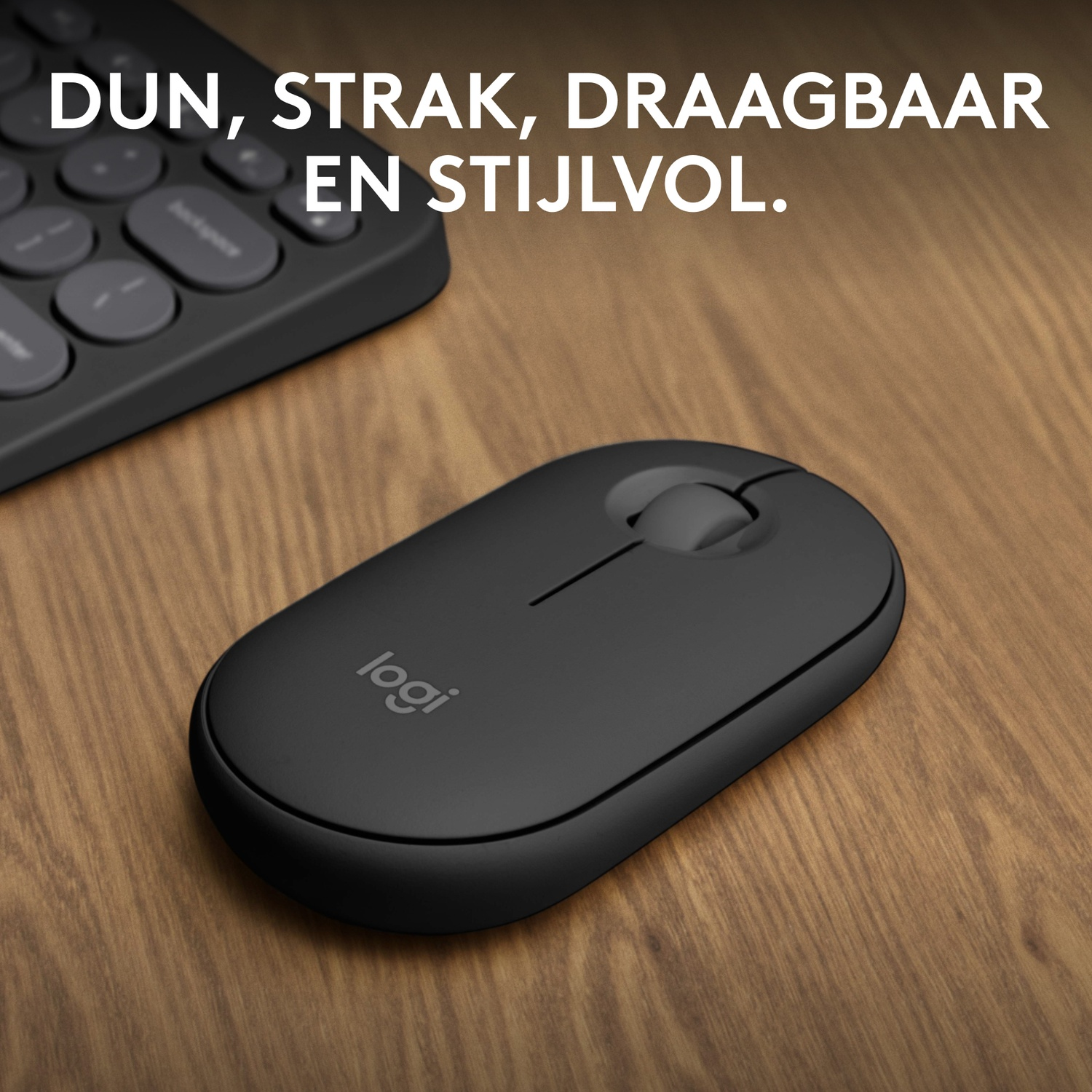 A black Logitech mouse on a wooden table, next to a keyboard.