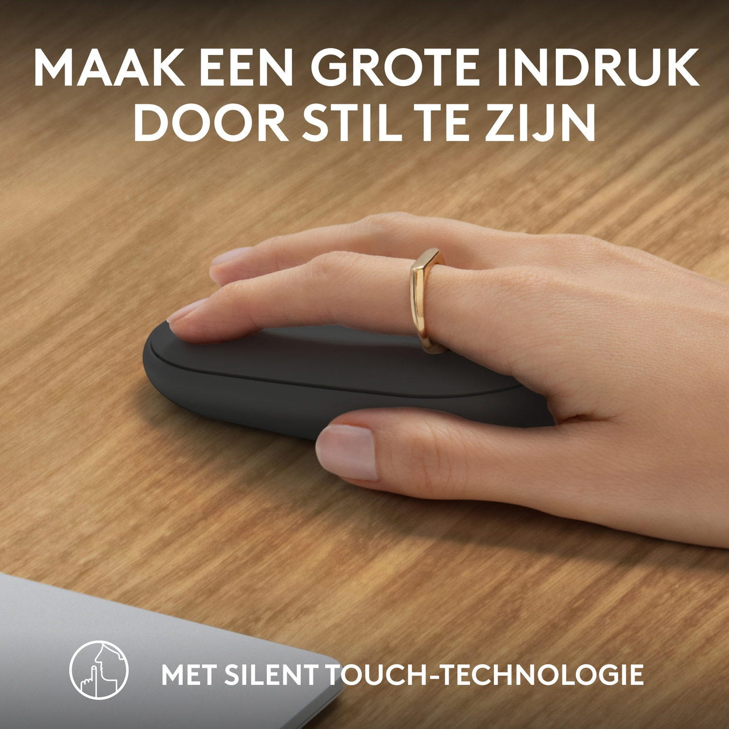A hand wearing a gold ring is touching a black mouse on a wooden surface, with text at the bottom.