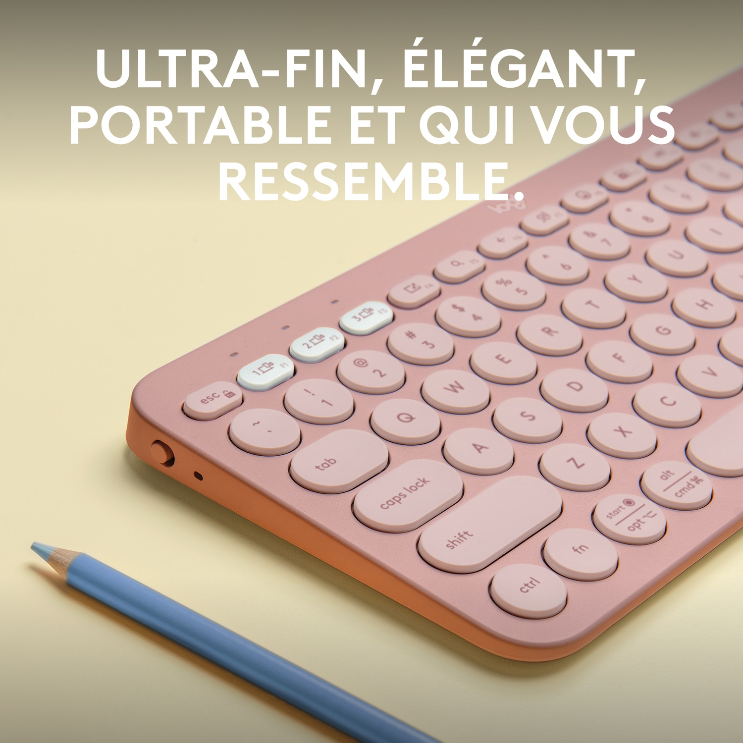Un clavier rose avec des touches blanches et un crayon bleu sur une surface jaune.