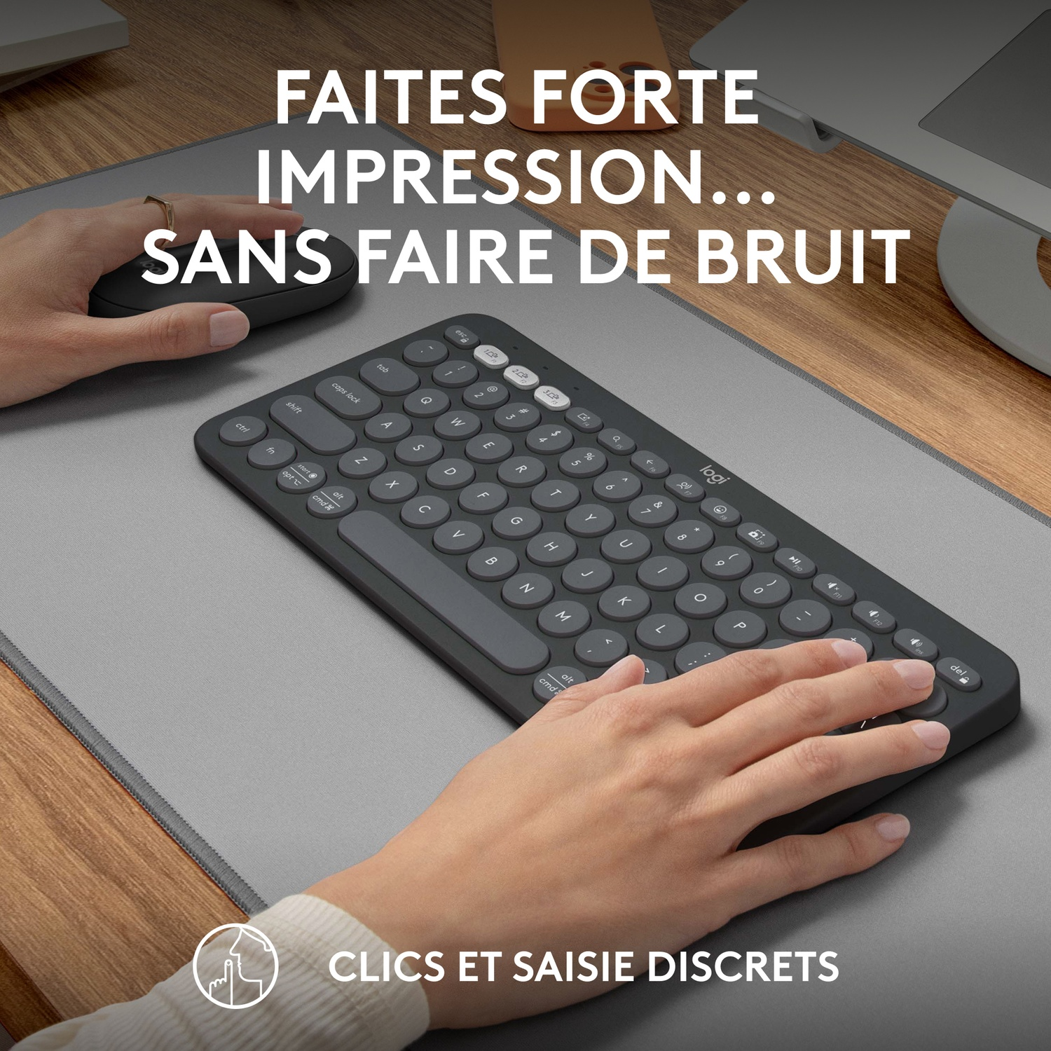 Mains tapant sur un clavier noir sur un tapis de souris gris. La souris est à côté.