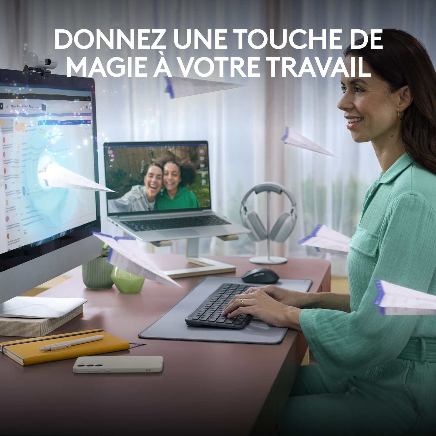 Une femme sourit en utilisant un ordinateur avec des avions en papier, un ordinateur portable et un casque sur un bureau.