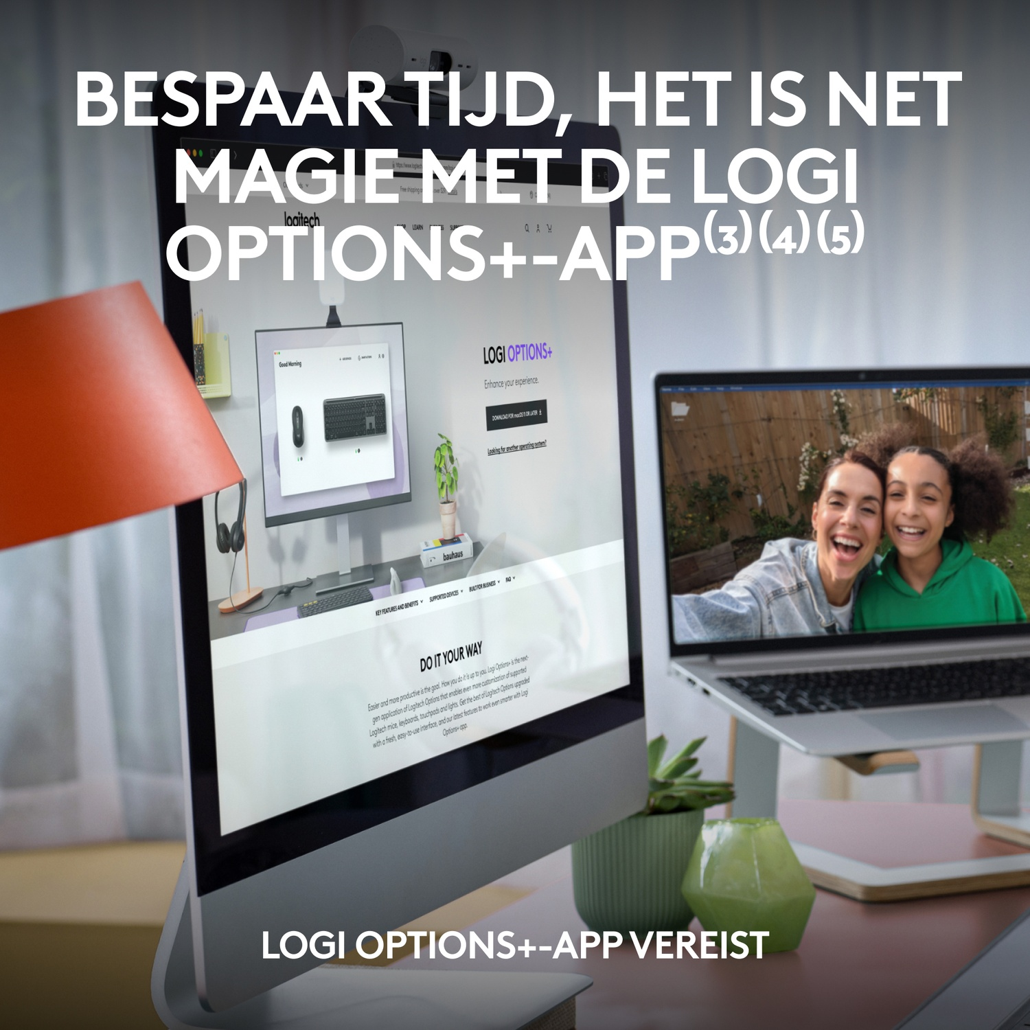 A desktop setup with a monitor displaying Logitech software. A laptop with two women on screen. Orange lamp on left.