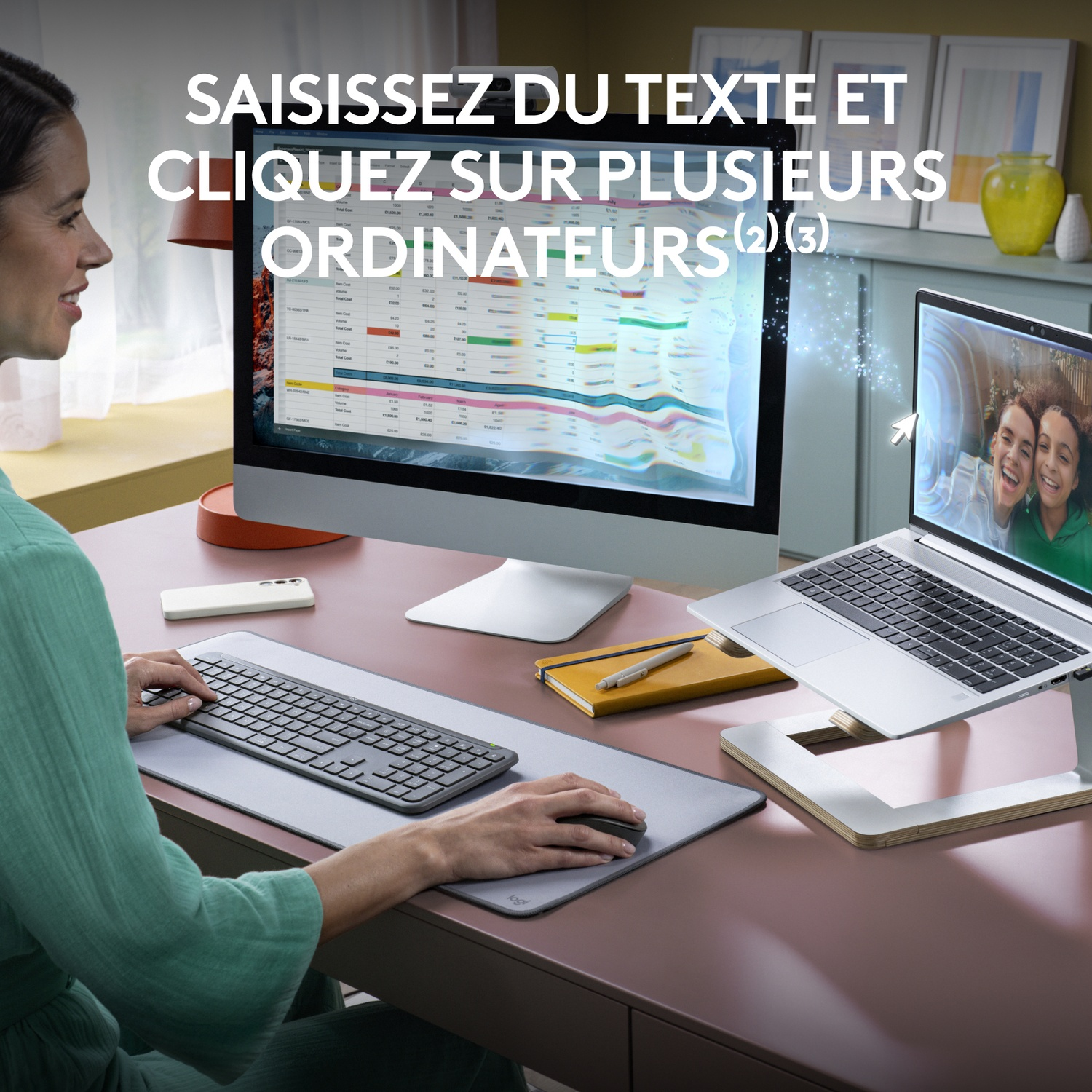 Une femme utilise une configuration clavier et souris avec plusieurs écrans. Souriant à un écran d'ordinateur portable.
