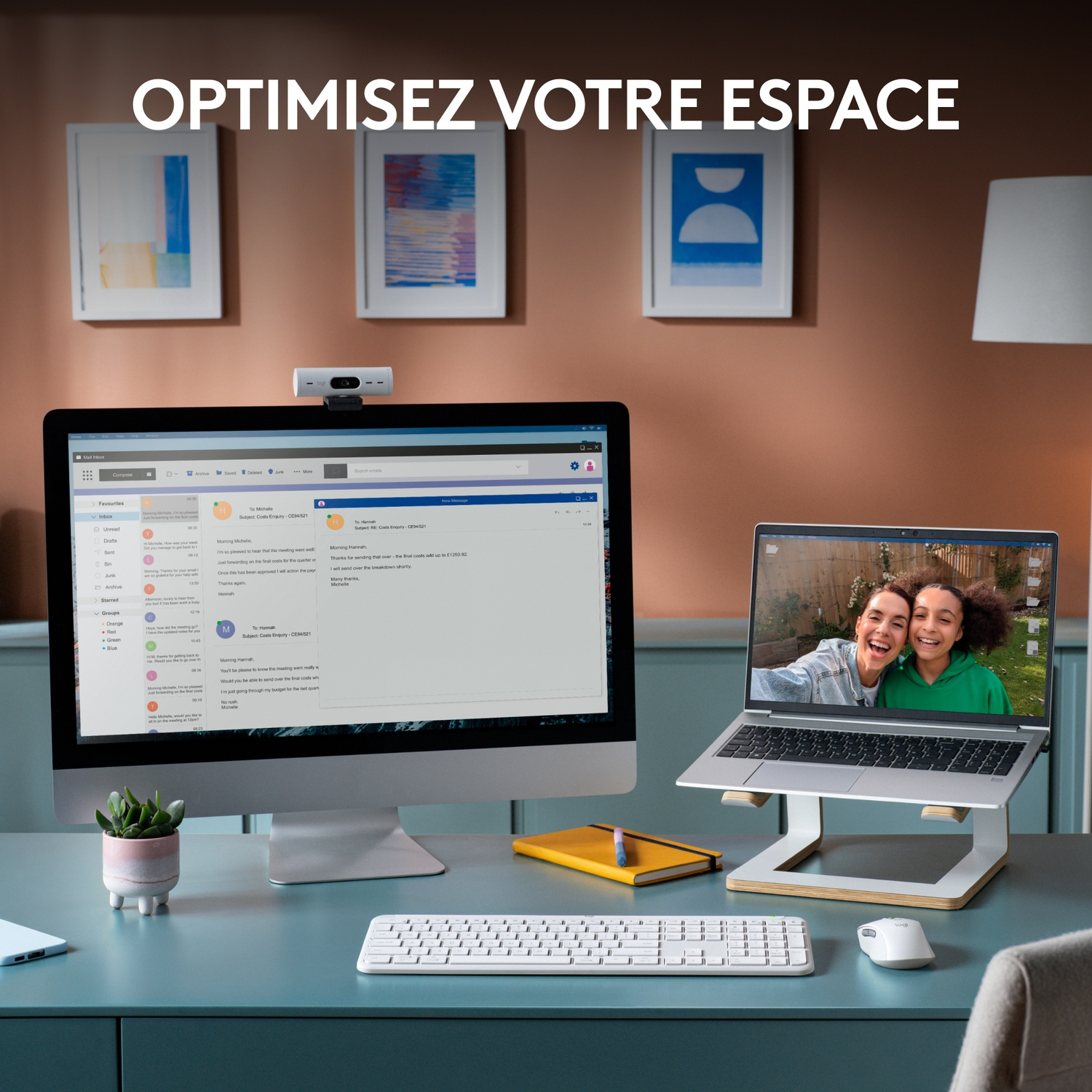 Bureau avec moniteur, ordinateur portable et clavier. Deux femmes souriantes sur l'écran.