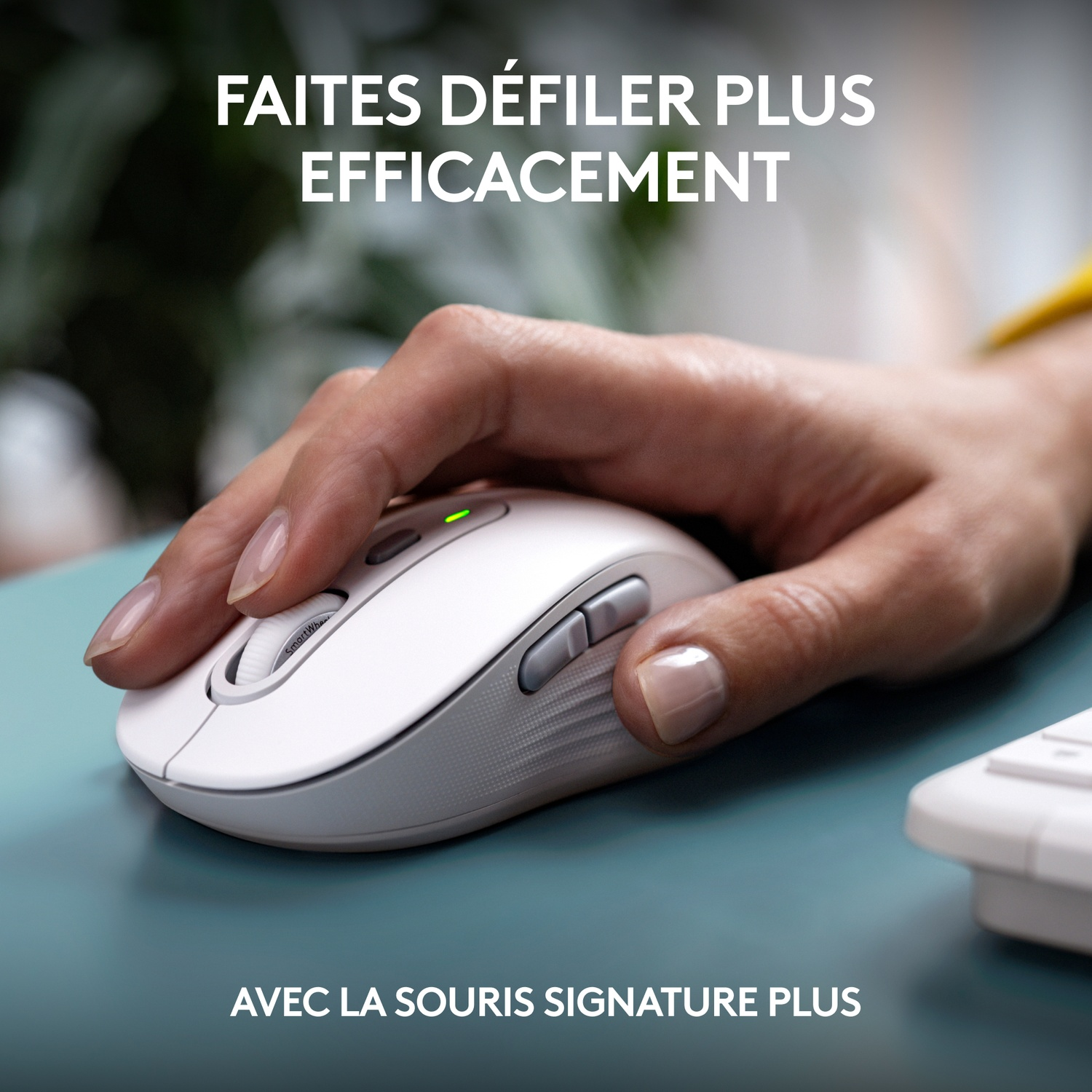 Main utilisant une souris blanche sur un bureau bleu sarcelle. La souris a une lumière verte.
