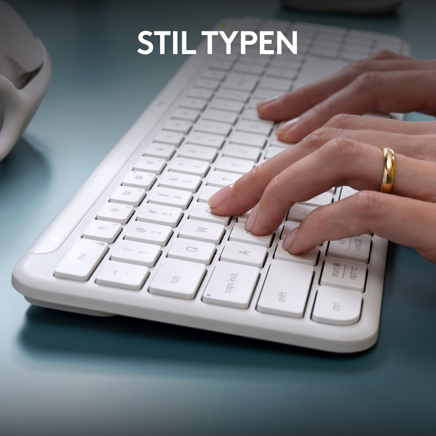 Hands typing on a white keyboard with a gold ring. Text at top reads 'stil typen'.