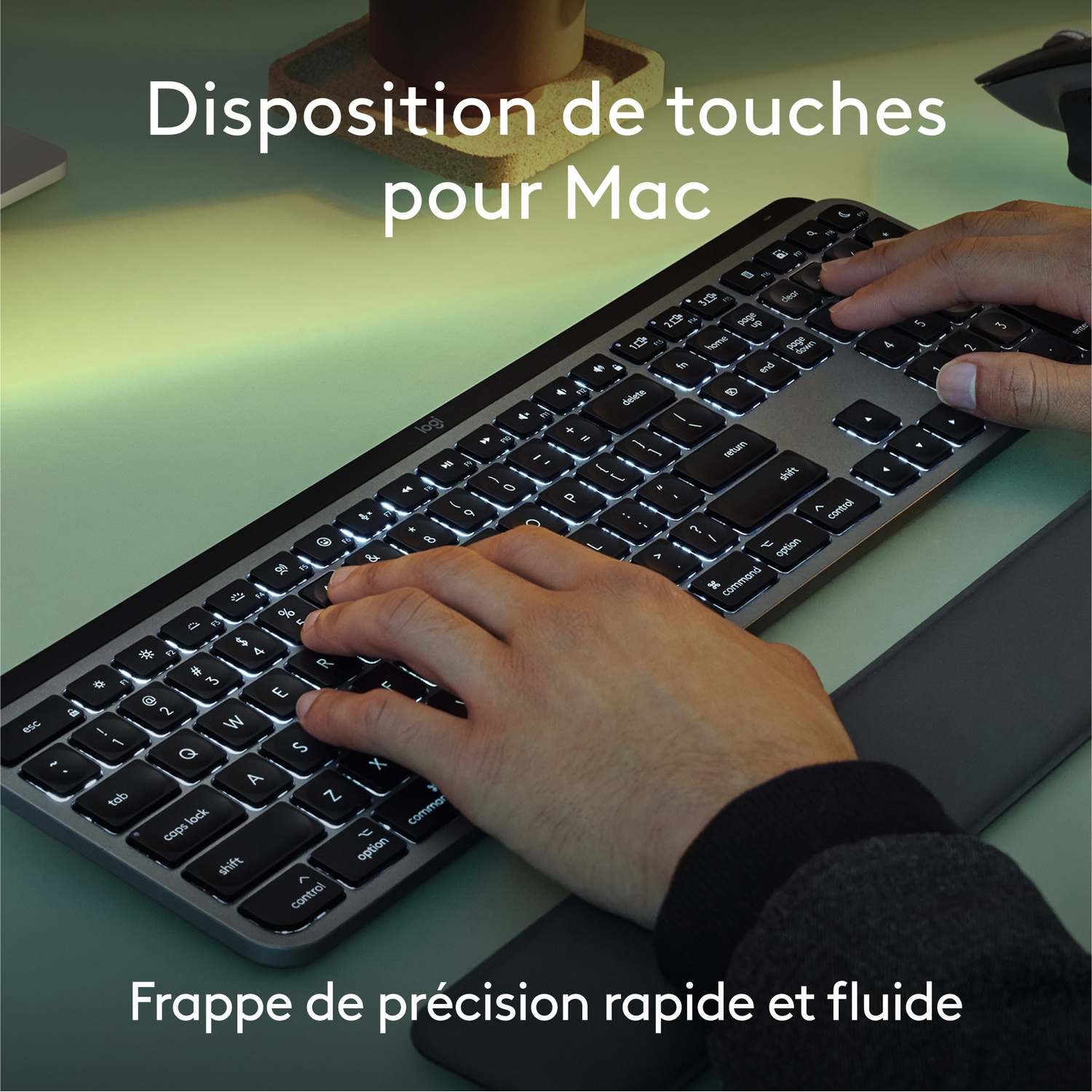 Une personne tape sur un clavier. Le clavier est rétroéclairé et argenté. Les mains sont visibles.