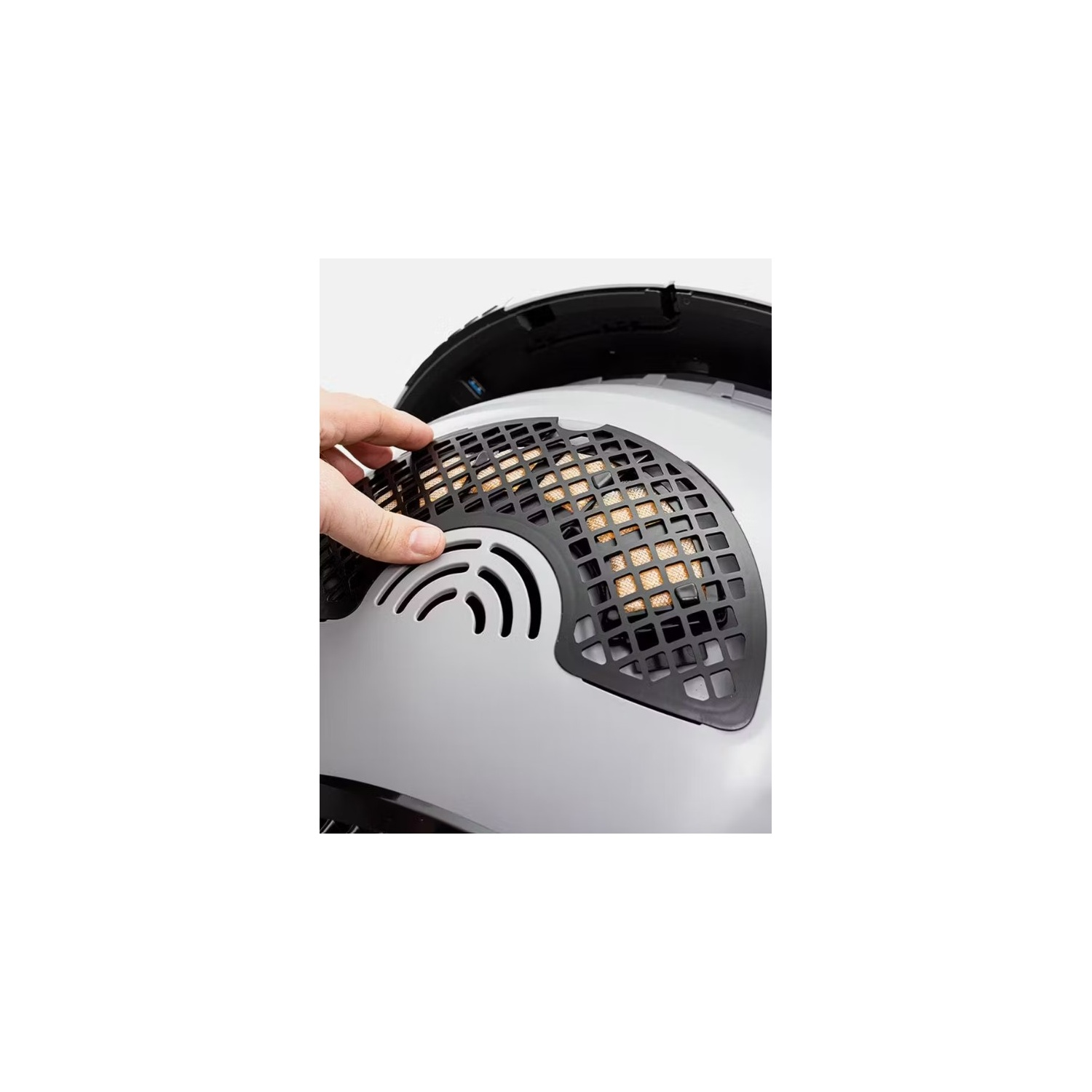 A hand is touching a fan inside a device. The fan is covered with a black grid.