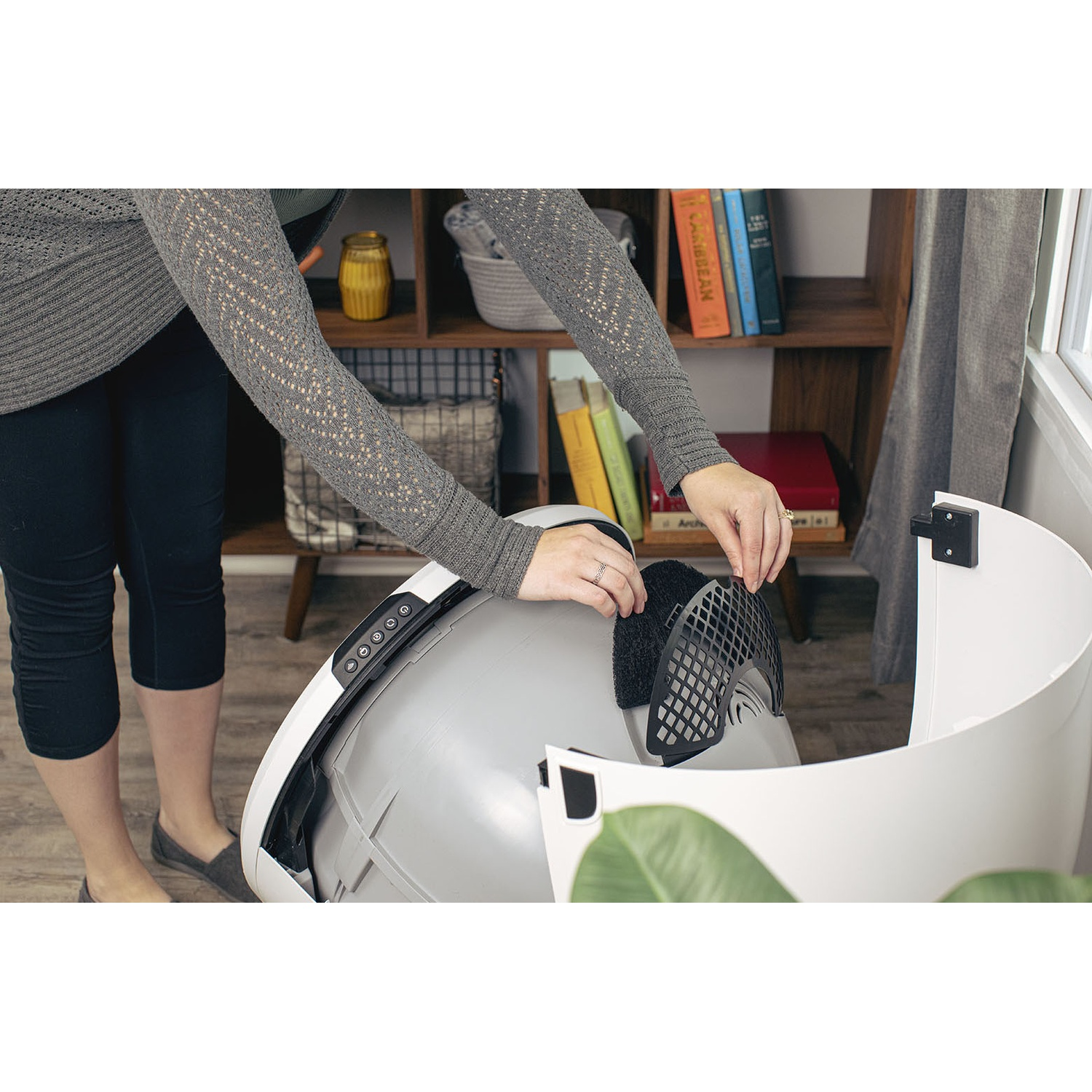 Person inserting a part into a white and gray pet care device.
