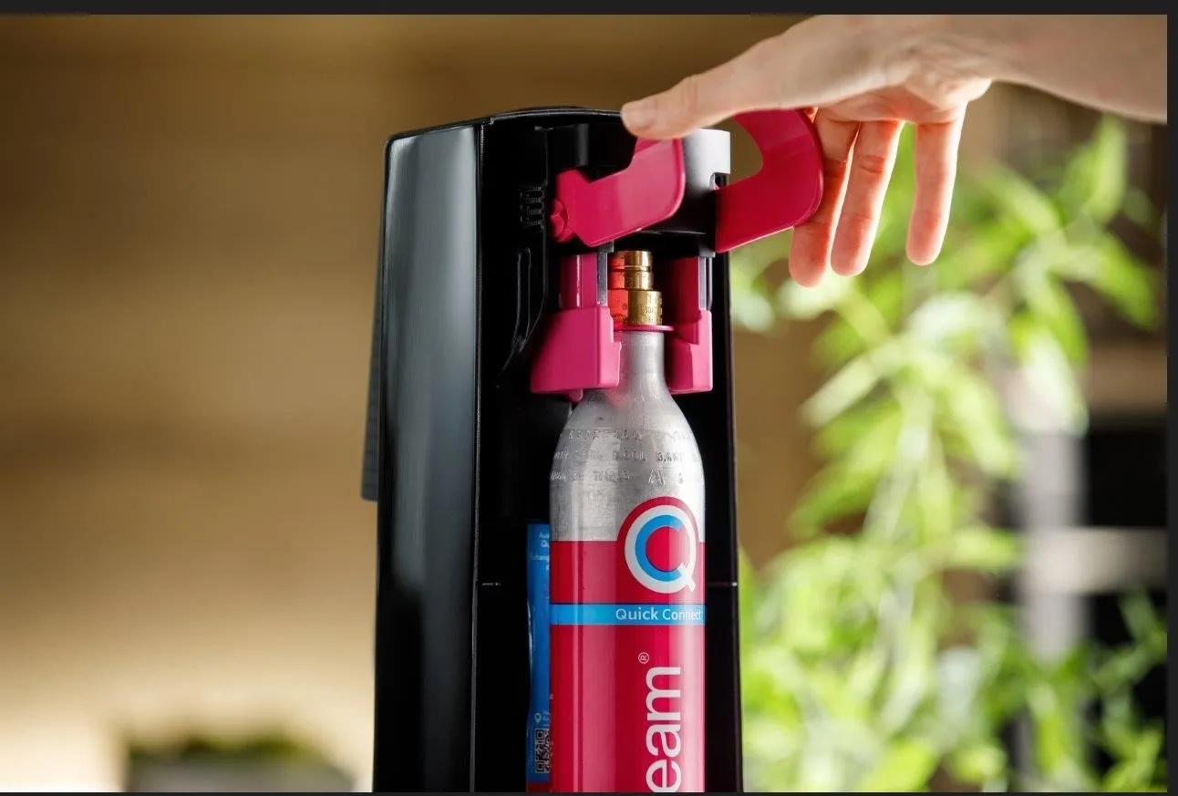 Ręka osoby obsługująca czarno-różowy saturator.