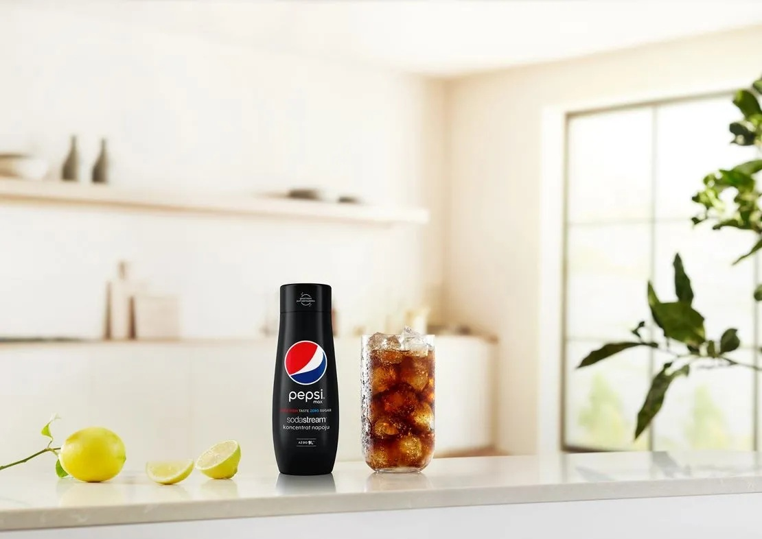 Butelka Pepsi Zero Sugar i szklanka Pepsi z lodem. Cytryna i limonki. Jasna kuchnia.