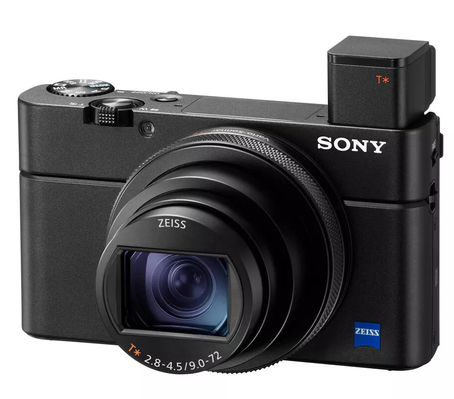 Czarny aparat Sony z obiektywem, akcesorium i logo Zeiss na obiektywie.