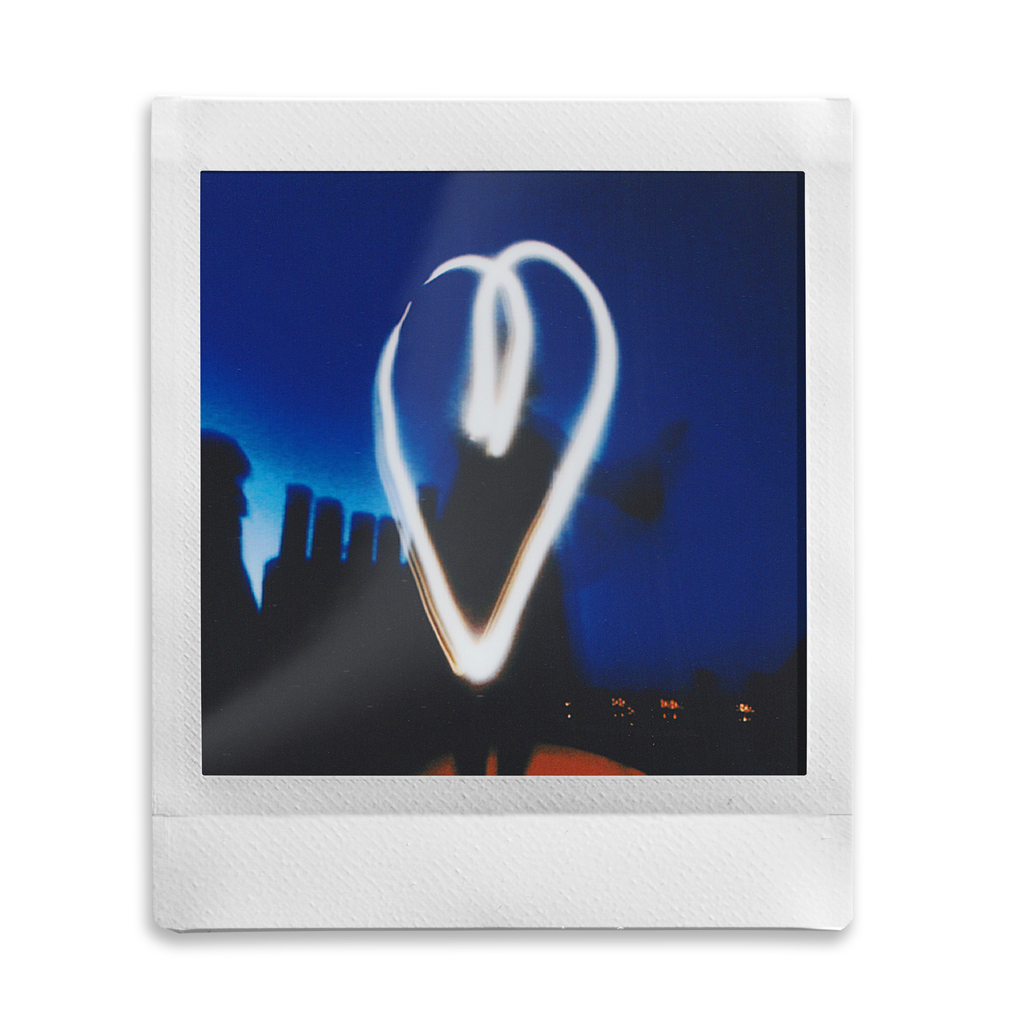 Photo polaroïd blanche avec un cœur de lumière sur un ciel bleu foncé.