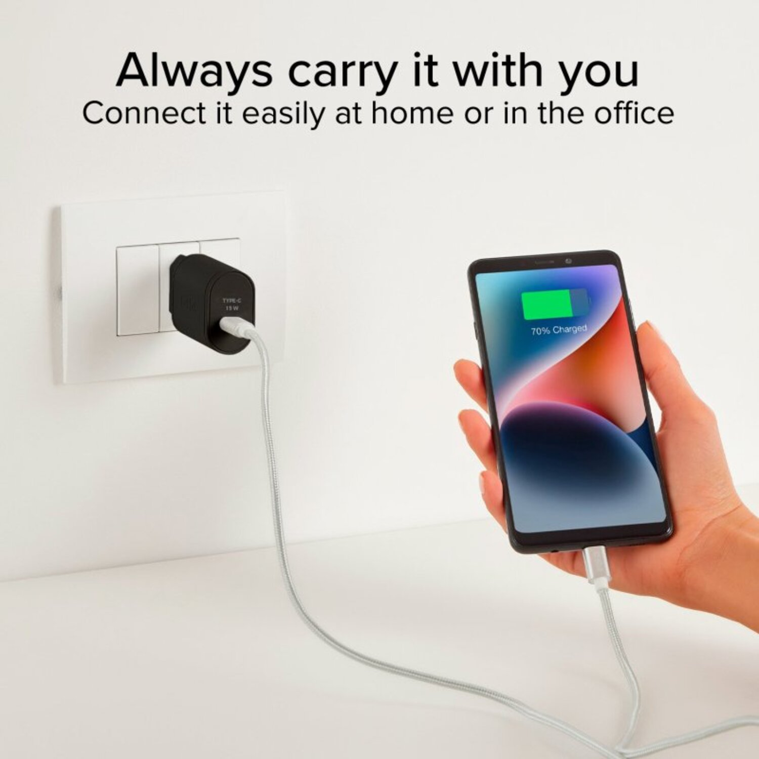 Un chargeur noir est branché sur une prise murale, chargeant un téléphone à 70 %.
