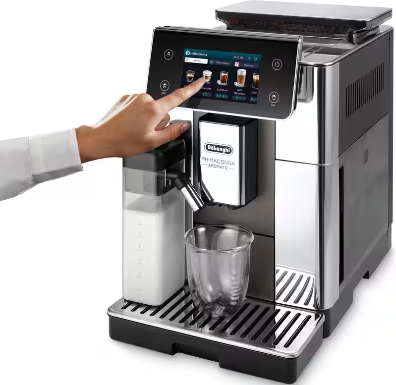 Una macchina da caffè con touchscreen viene toccata da una mano. Un contenitore per il latte e un bicchiere sono vicini.