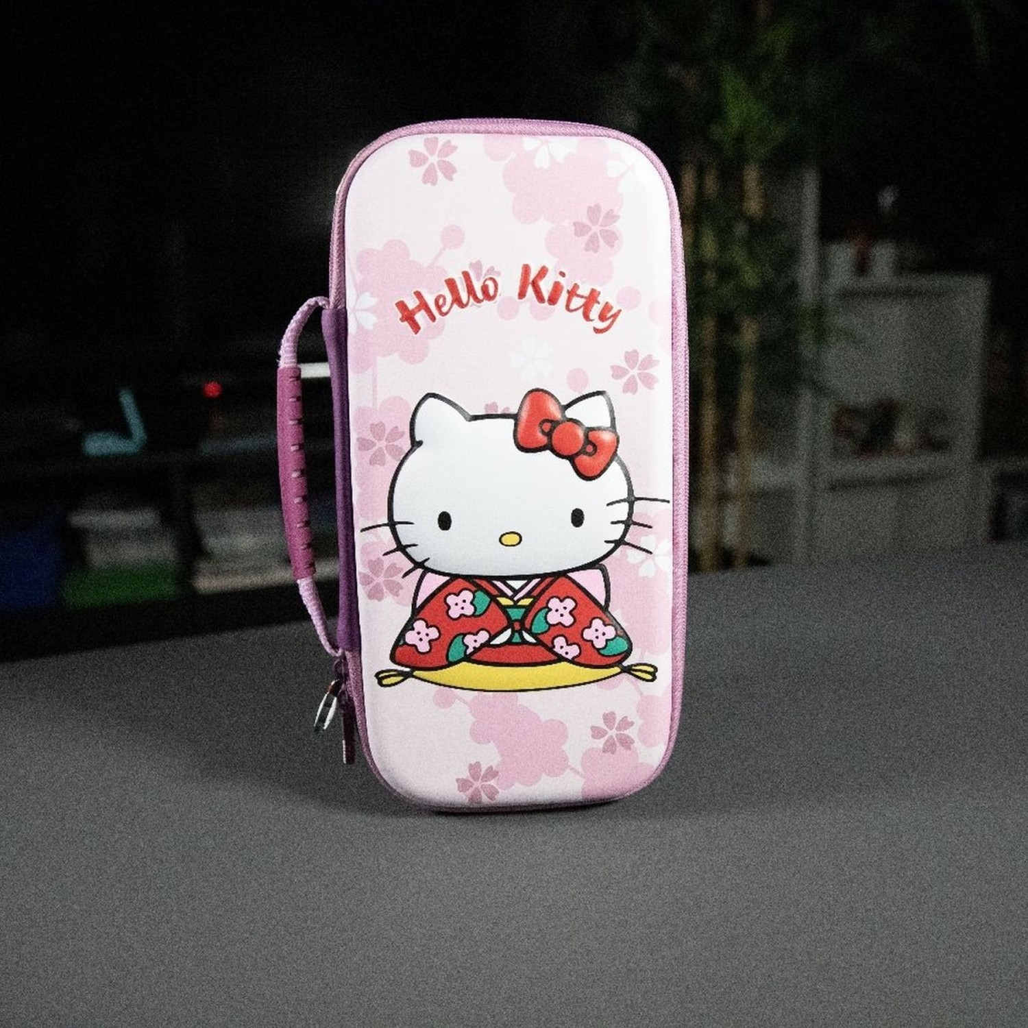 Une trousse Hello Kitty rose avec un dessin de Hello Kitty portant un kimono. Des fleurs de cerisier en arrière-plan.