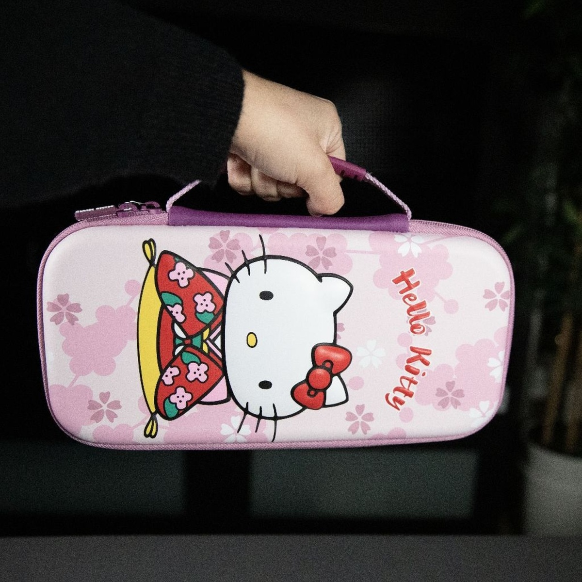 Étui Hello Kitty tenu par une main. Design rose avec image Hello Kitty.