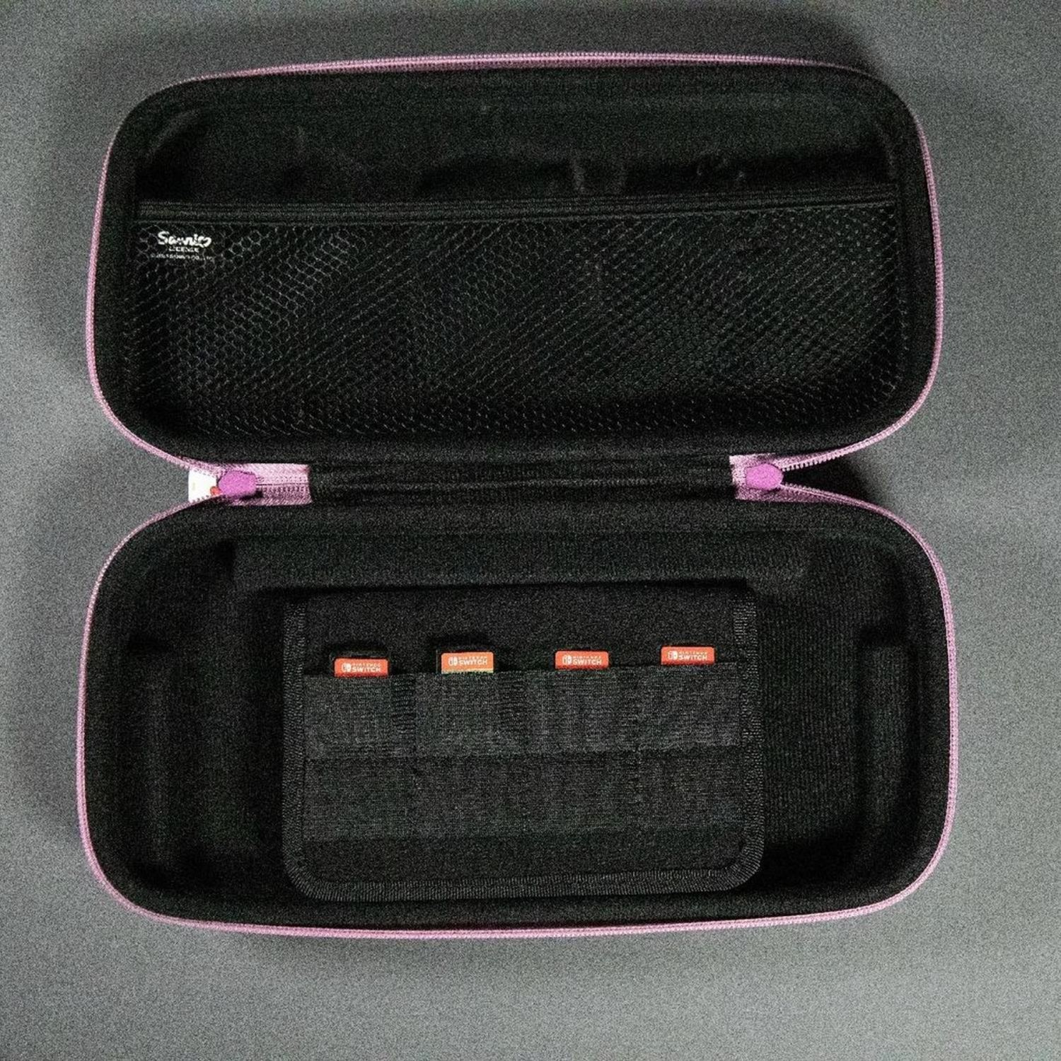 Étui Nintendo Switch rose ouvert, révélant des emplacements pour cartes de jeu et une poche en filet.