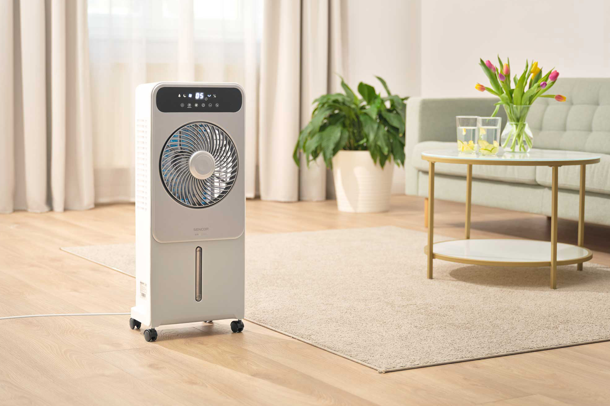 Fehér légkondicionáló egy nappaliban, ventilátorral és más bútorokkal a háttérben.