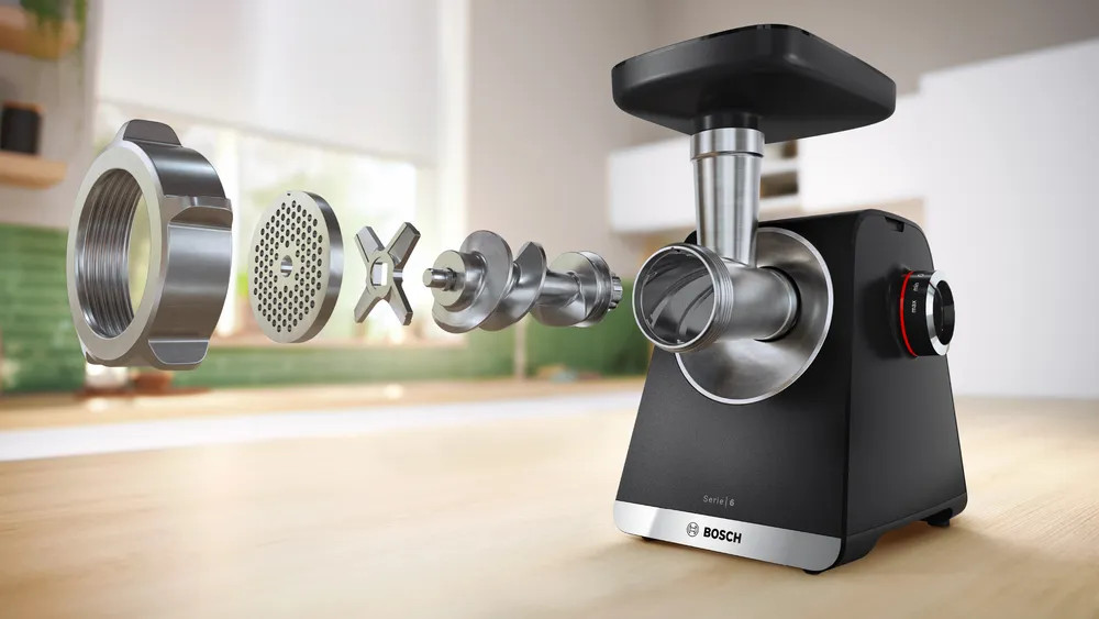 Rozłożona maszynka do mięsa, pokazująca części od lewej do prawej.