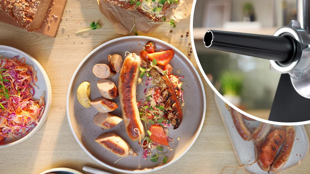 Talerz grillowanej kiełbasy z dodatkami. Kiełbasa, pomidory, zielenina i chleb na stole.