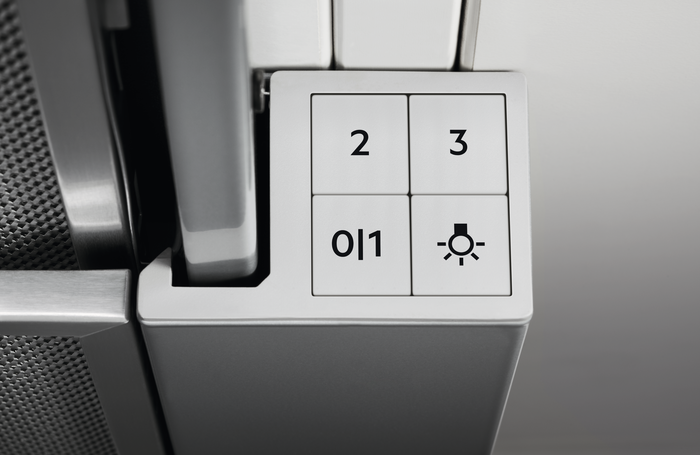Nahaufnahme eines weißen Dunstabzugshauben-Bedienfelds mit den Tasten 0/1, 2, 3 und einem Licht.