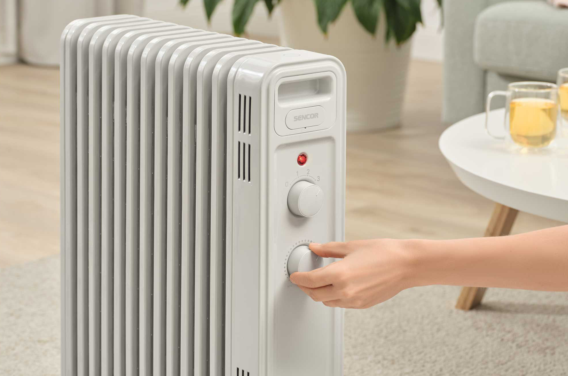 Egy személy beállít egy fehér elektromos radiátort a nappaliban.