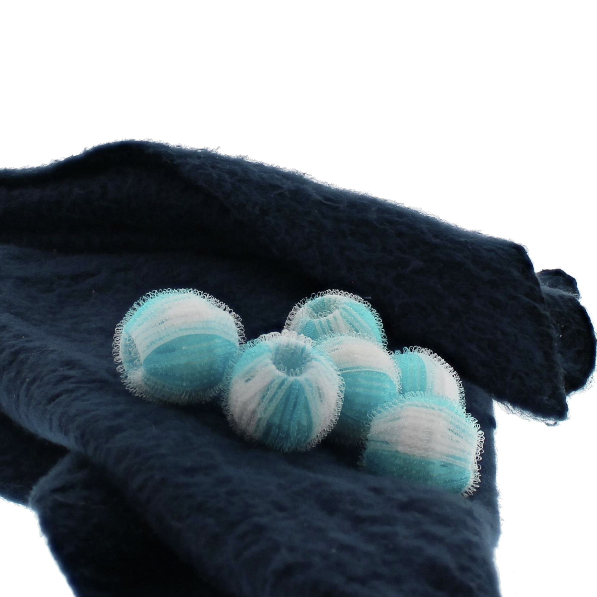 Bolas de lavandería azules y blancas sobre un paño azul marino. Las bolas están delante del paño.