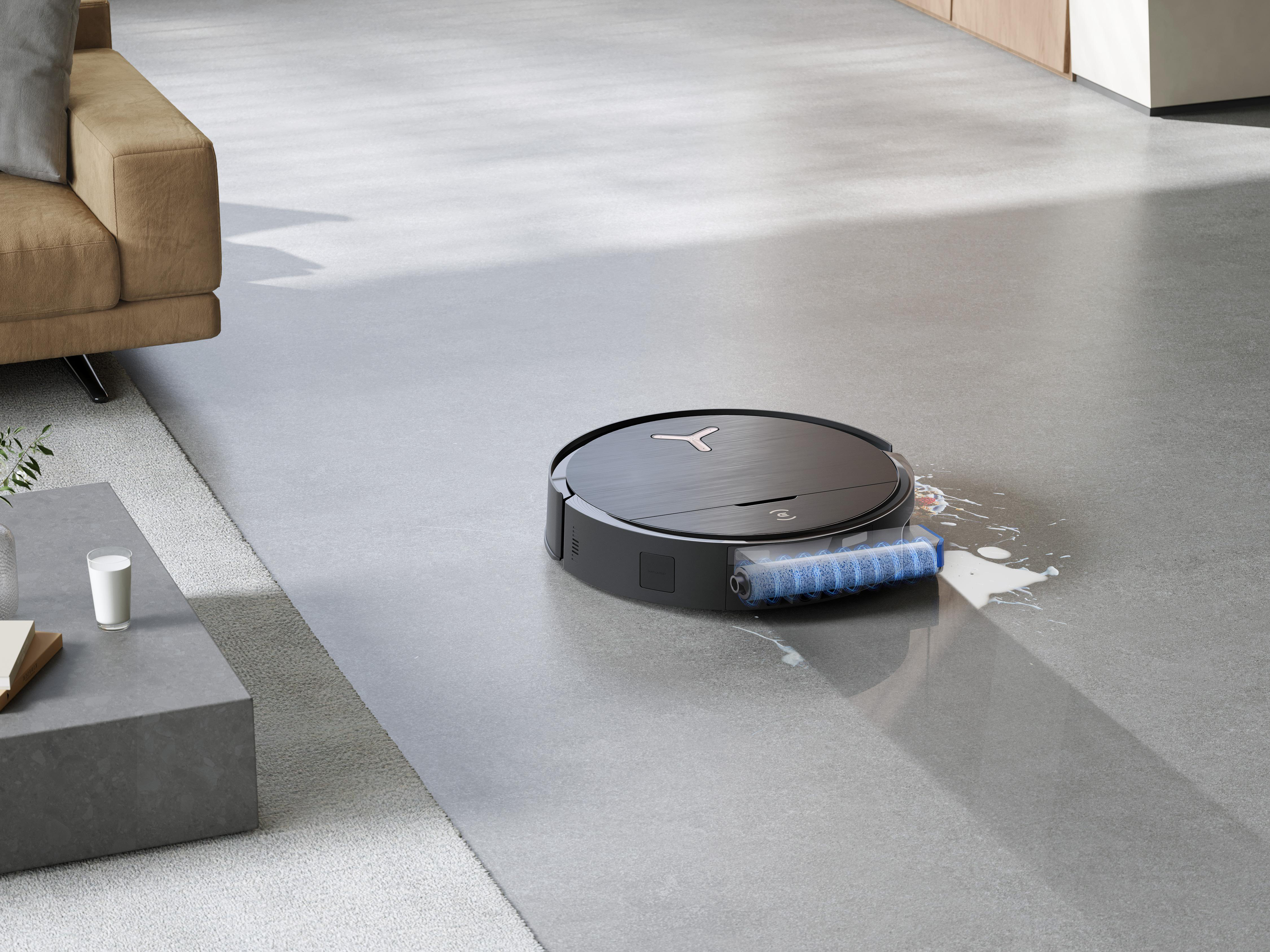 Roboter-Staubsauger reinigt einen Boden, mit Couch und Tisch im Hintergrund.