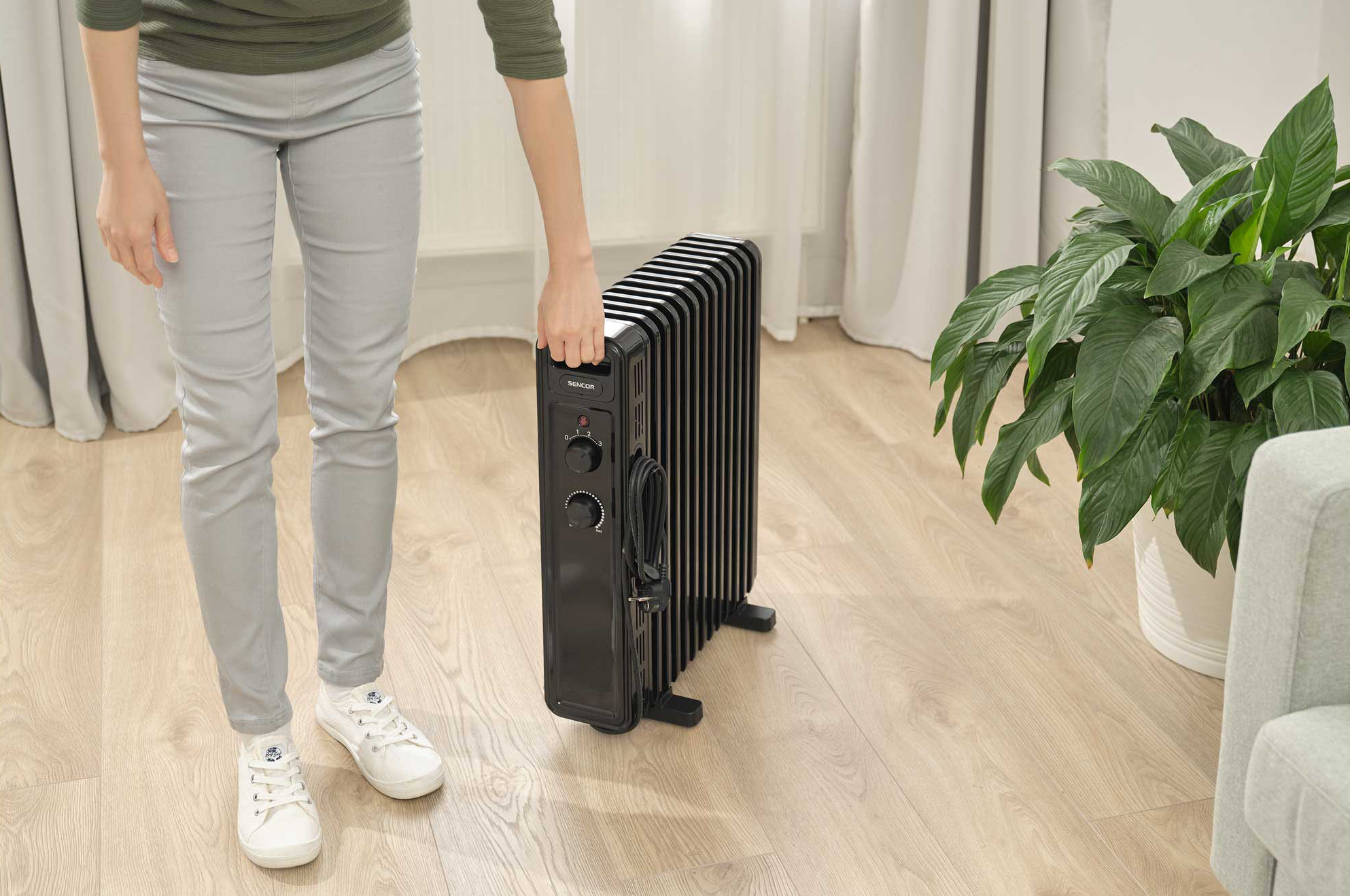 Egy személy egy fekete radiátort tart egy növény mellett.