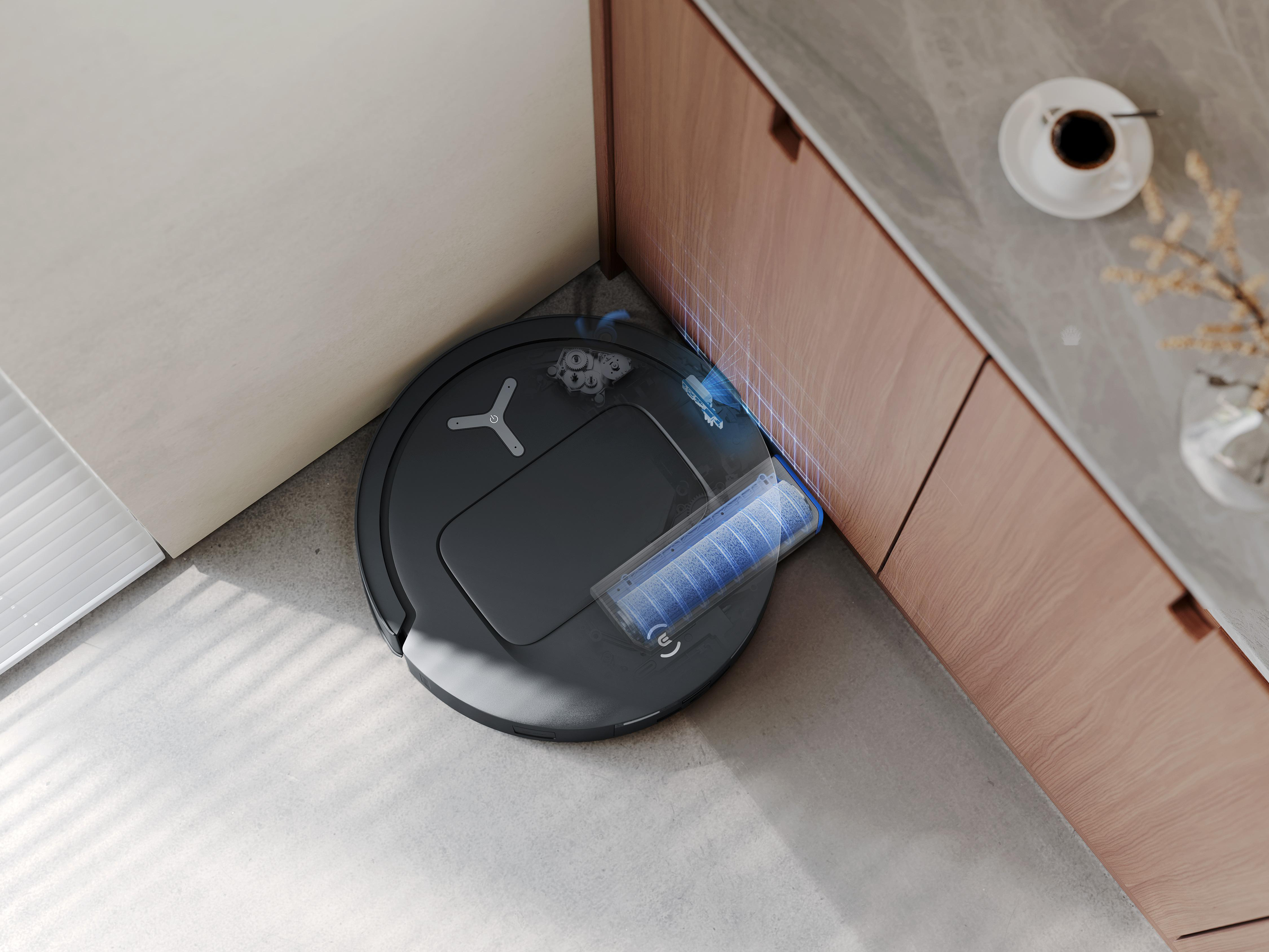 Ein schwarzer Roboter-Staubsauger in einer Ecke, in der Nähe von Schränken. Der Reiniger steht auf hellem Boden.