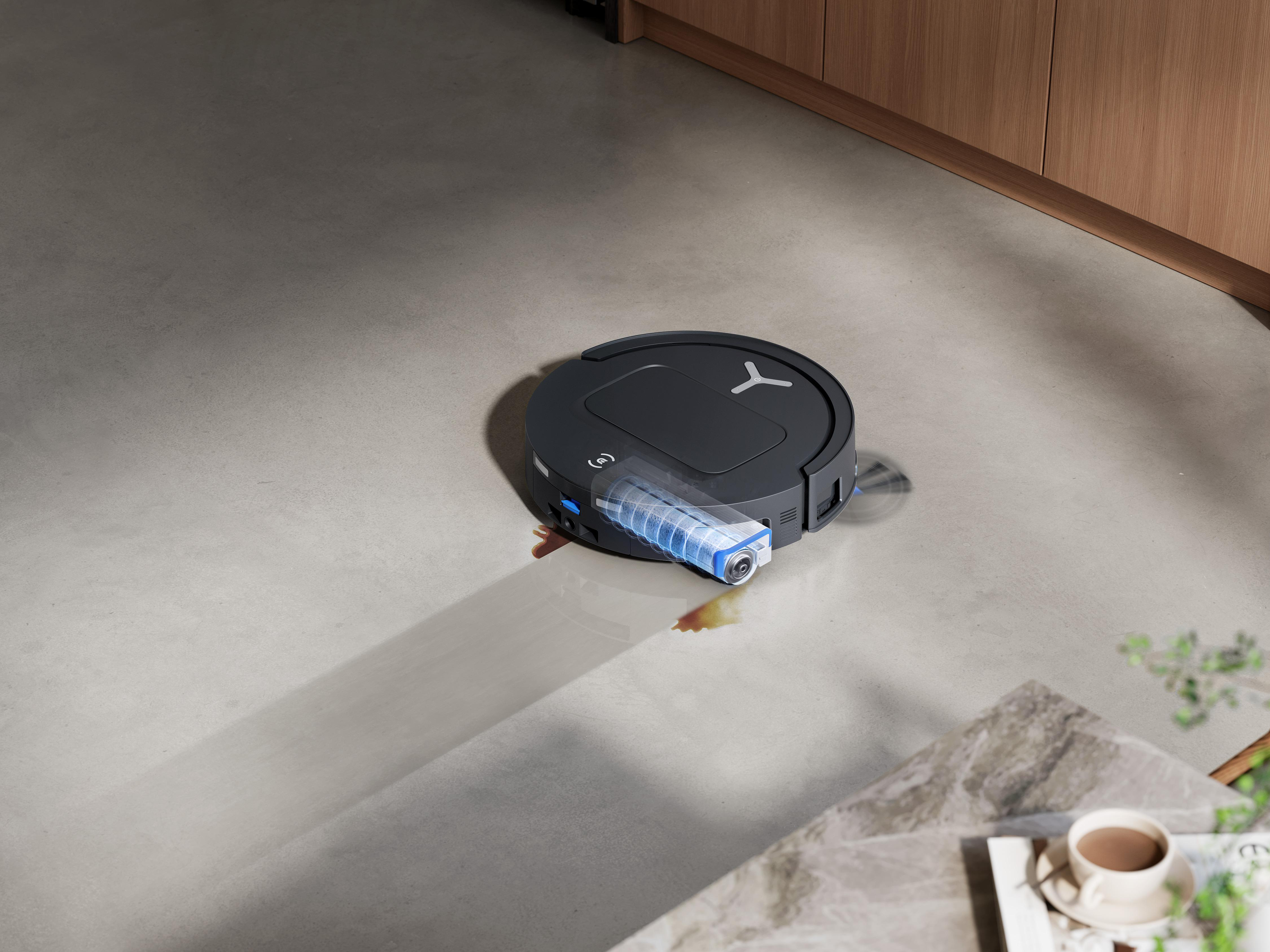 Ein schwarzer Roboter-Staubsauger auf einem hellgrauen Boden, mit blauem Wassertank.