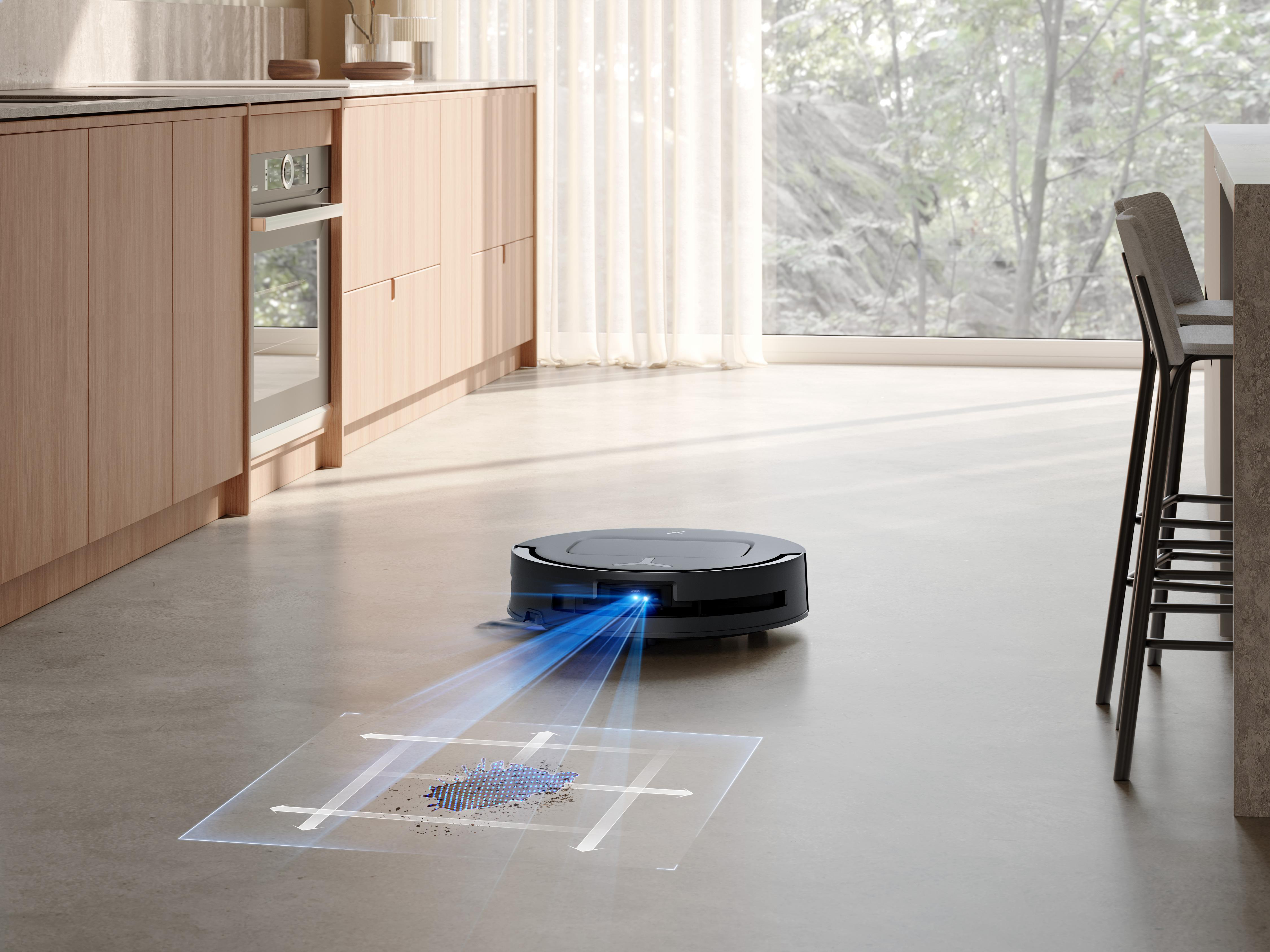 Roboter-Staubsauger reinigt einen Boden. Küche im Hintergrund.