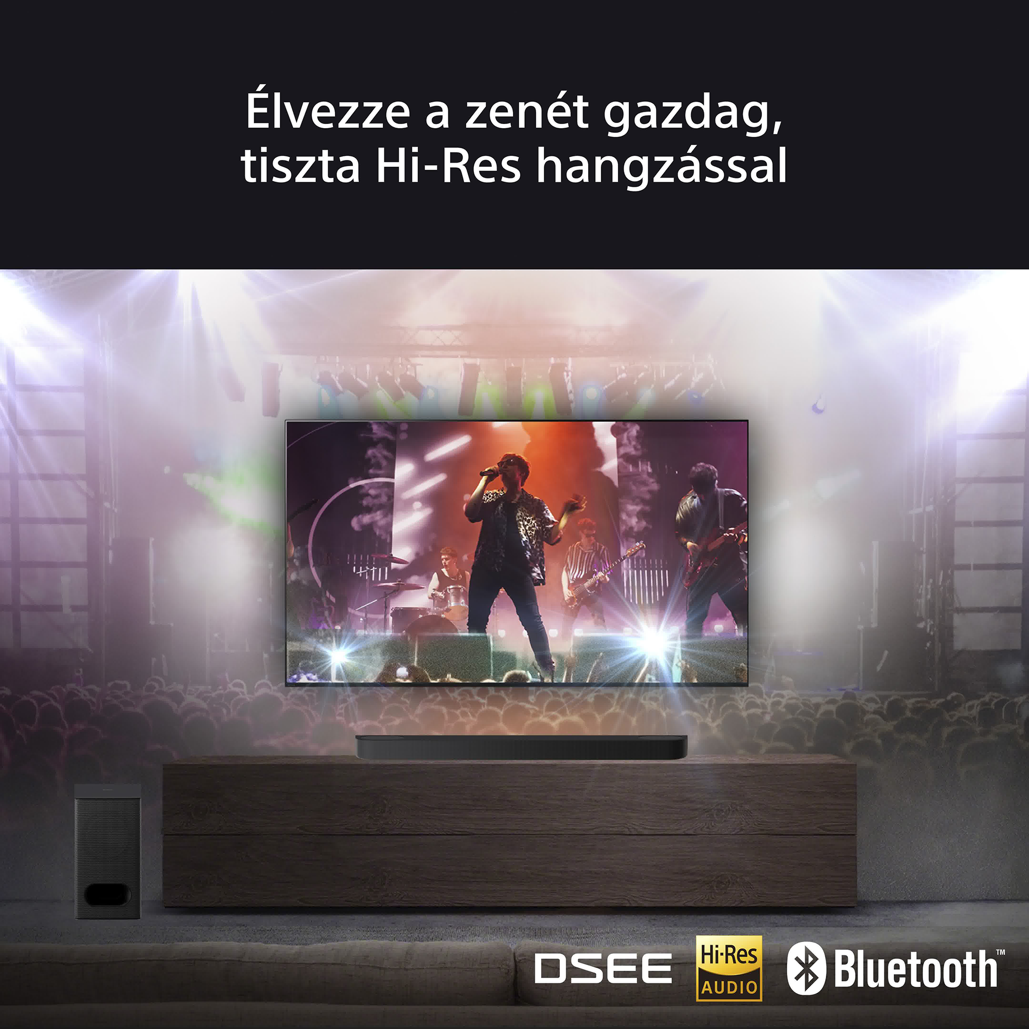Egy TV képernyő egy színpadon fellépő zenekart mutat. A TV előtt egy soundbar és egy mélynyomó található.