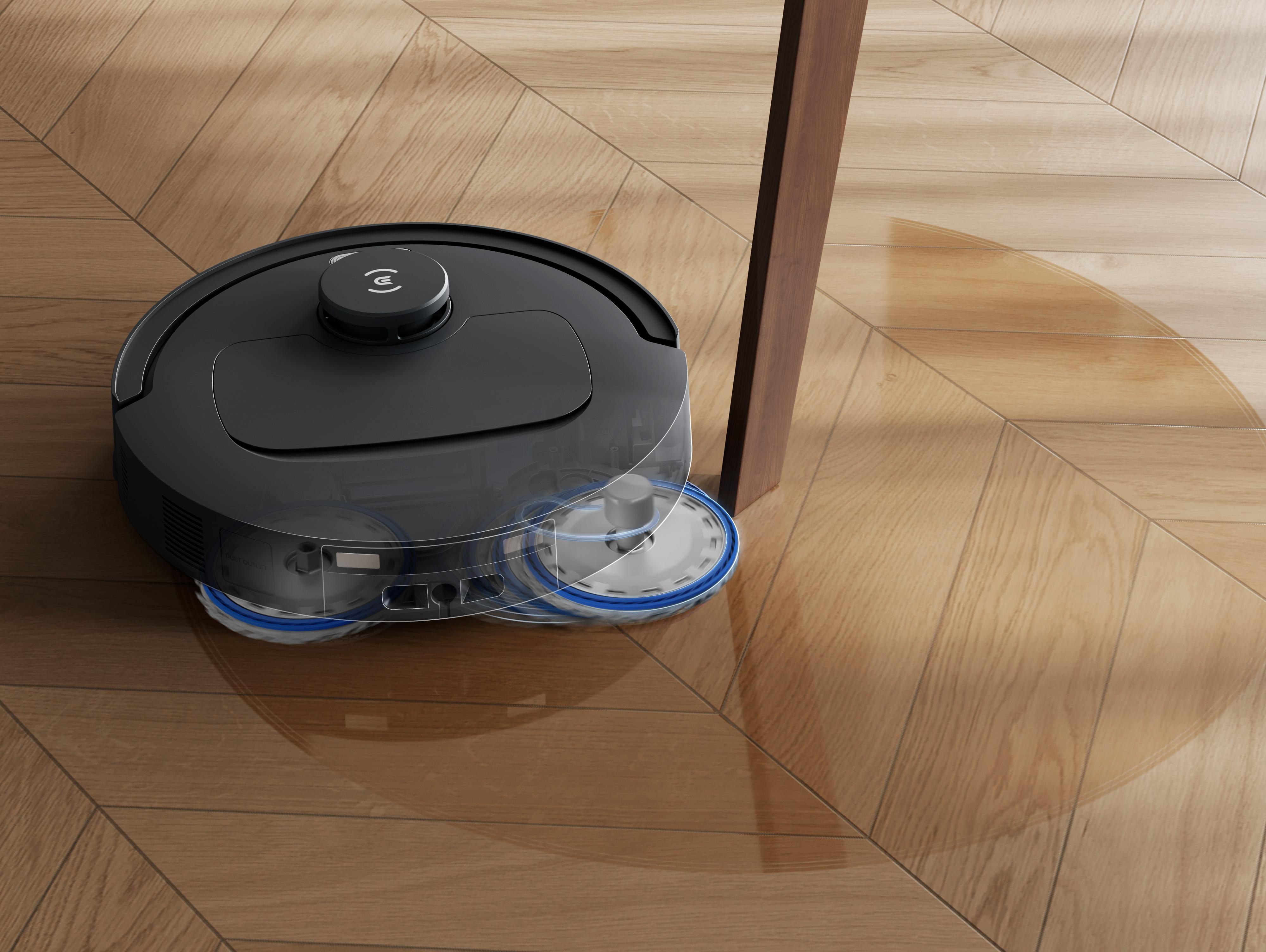 Ein Roboter-Staubsauger reinigt einen Holzboden und bewegt sich um das Bein eines Tisches herum.