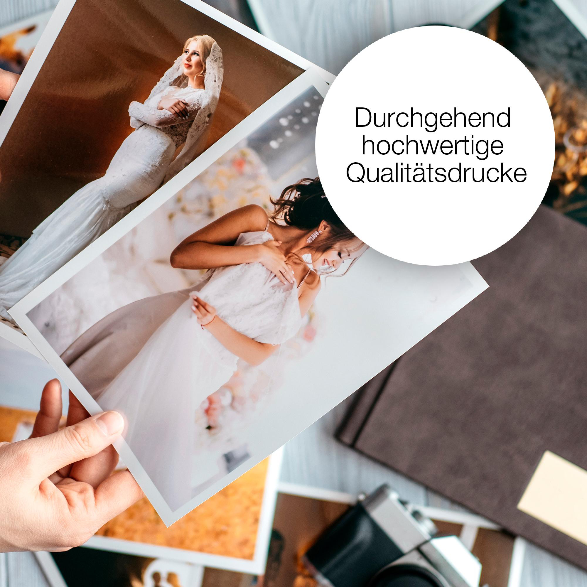 Hände halten Fotoabzüge einer Braut. Braunes Fotoalbum und Kamera liegen auf einem Holztisch.