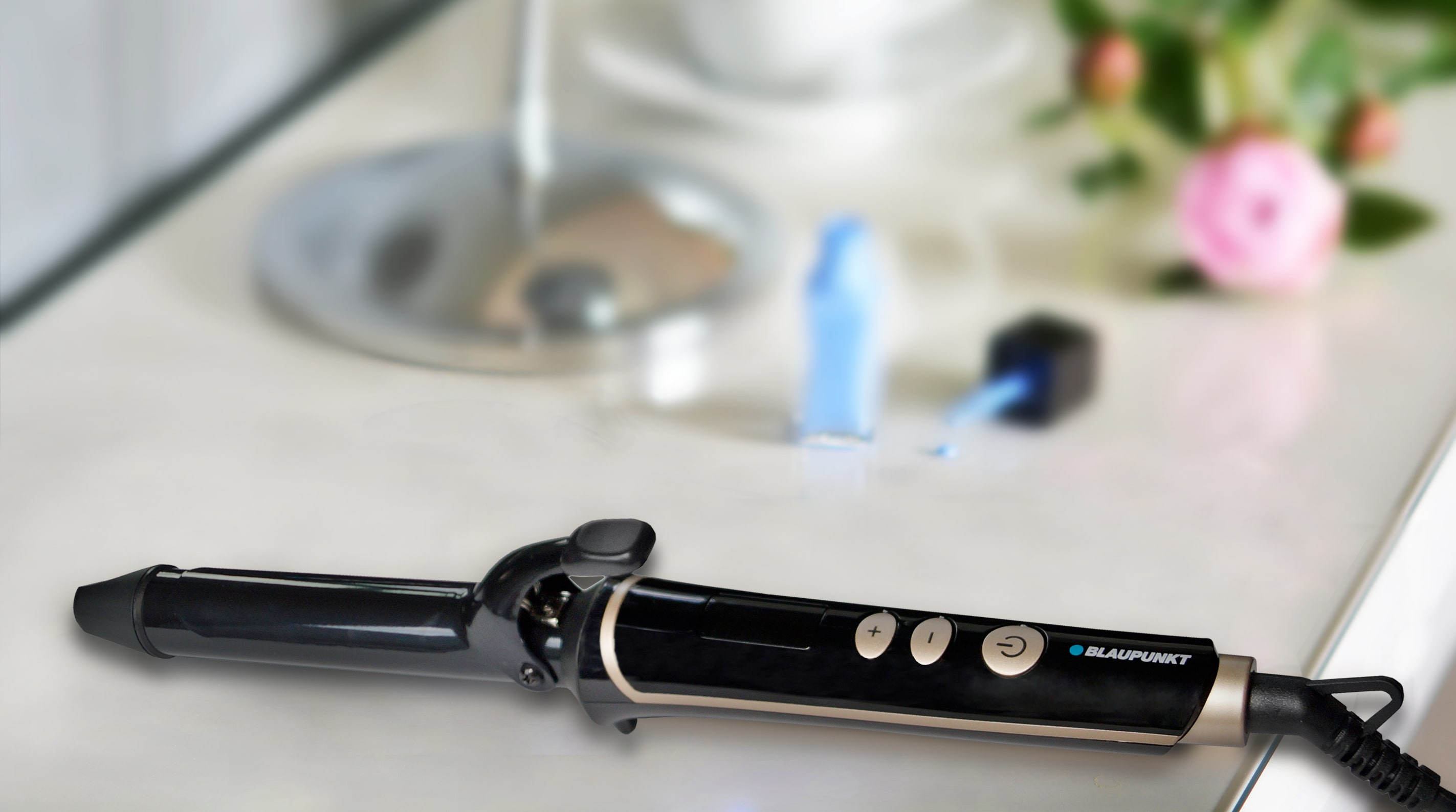 Lokówka na białej powierzchni z rozmytymi butelkami lakieru do paznokci w tle.